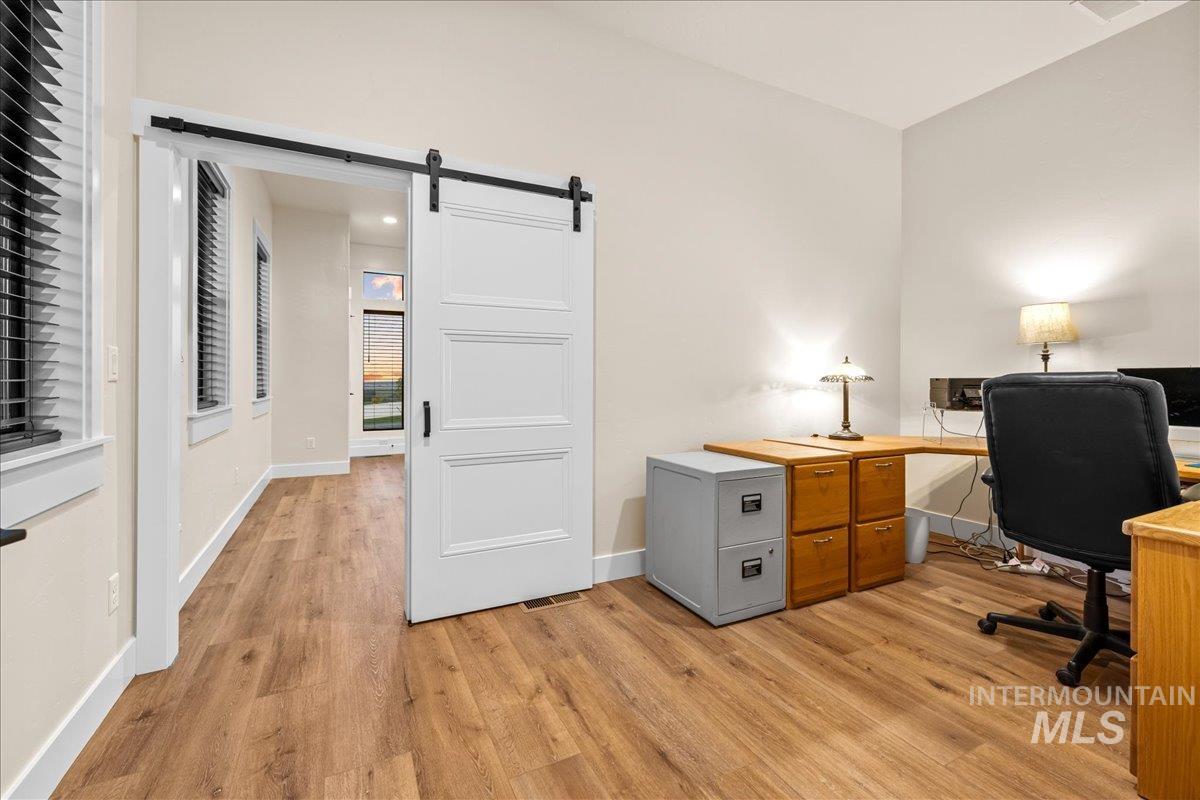 Office with light wood finished floors and a barn door