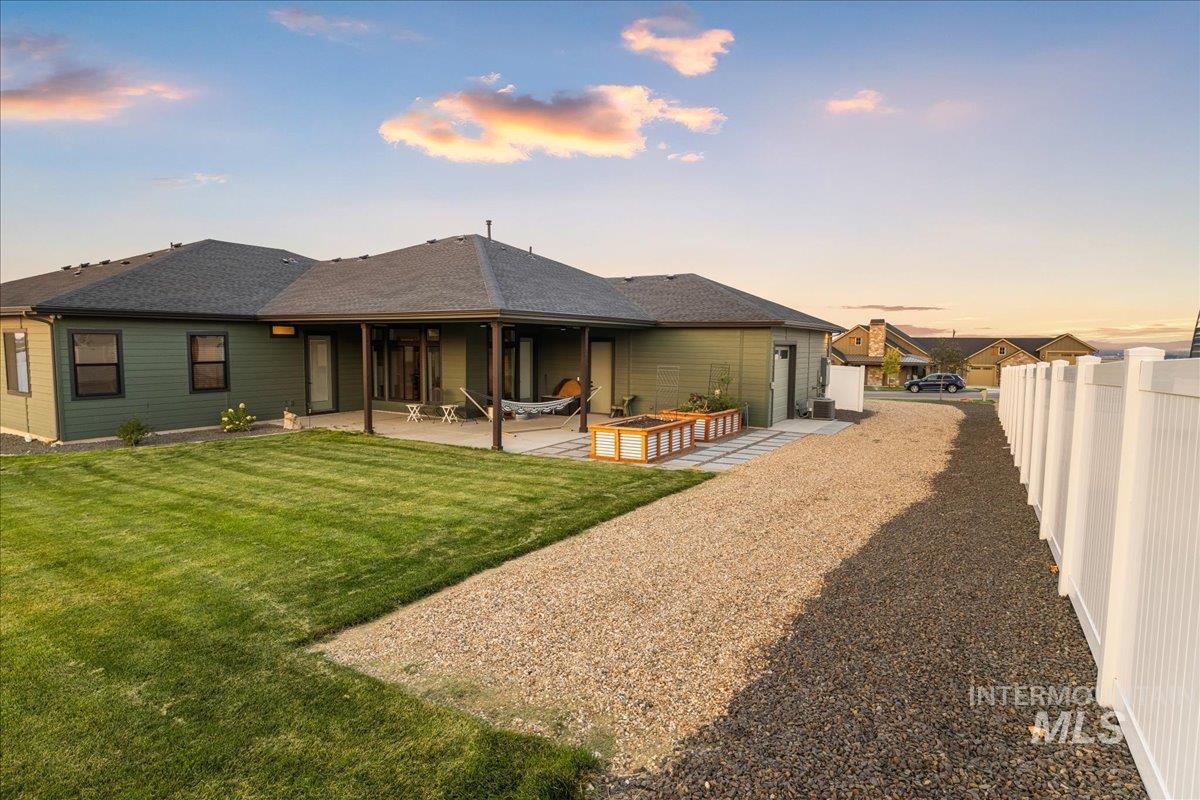 Back of property at dusk featuring a patio and roof with shingles
