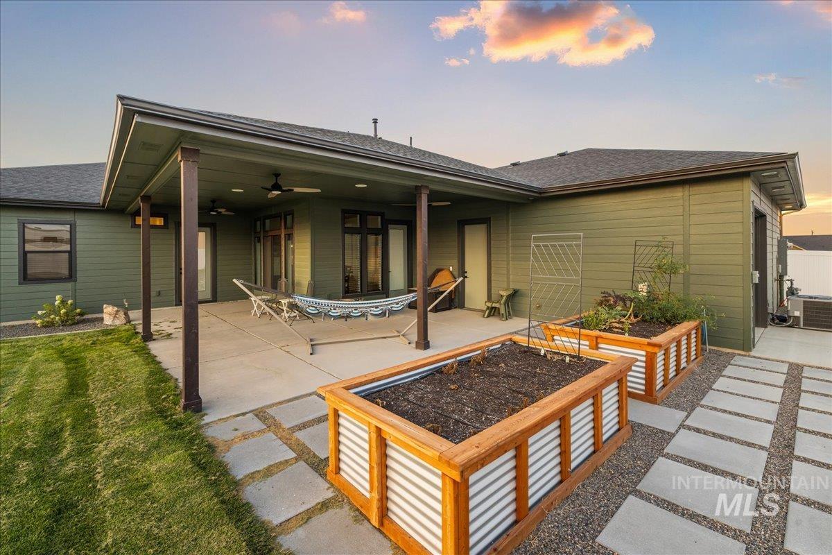 Rear view of property featuring a vegetable garden, a patio, roof with shingles, and ceiling fan