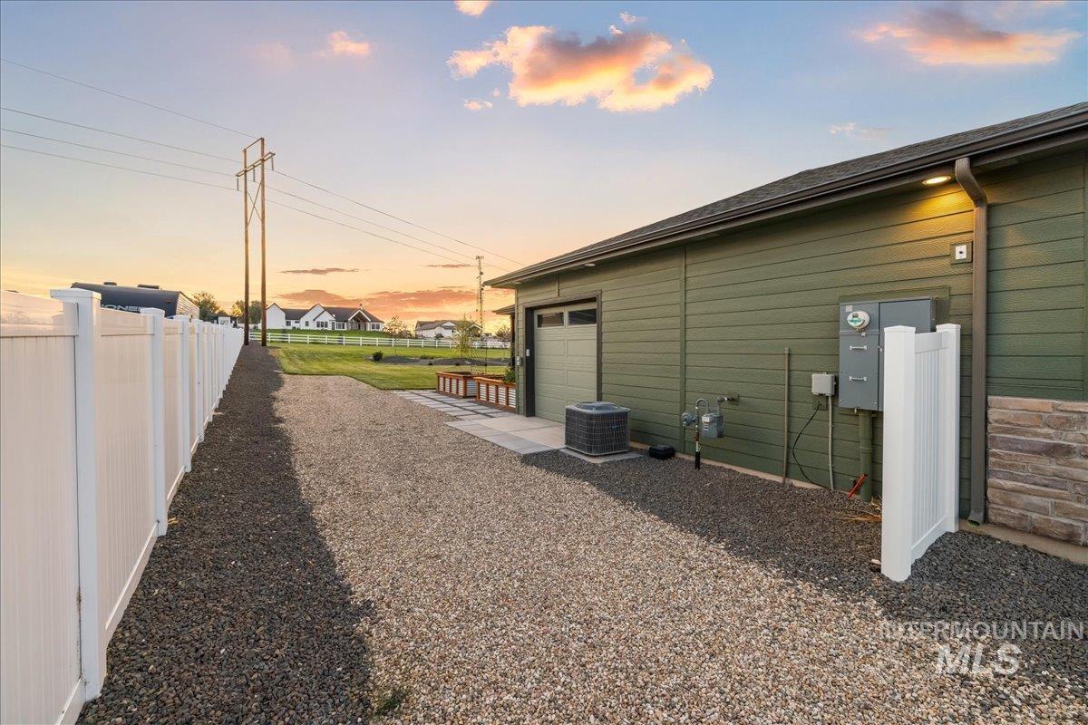 Property exterior at dusk featuring a garage and a cooling unit