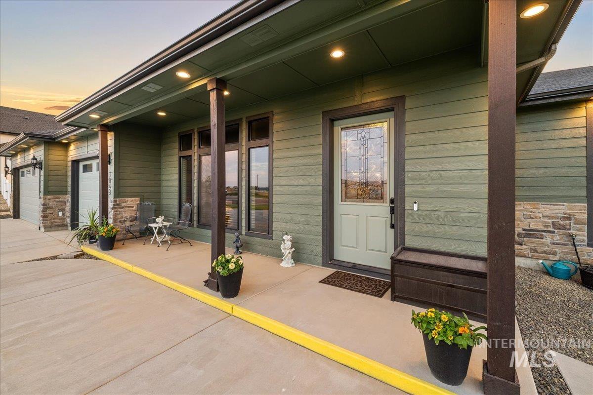 View of exterior entry with stone siding, a garage, and covered porch