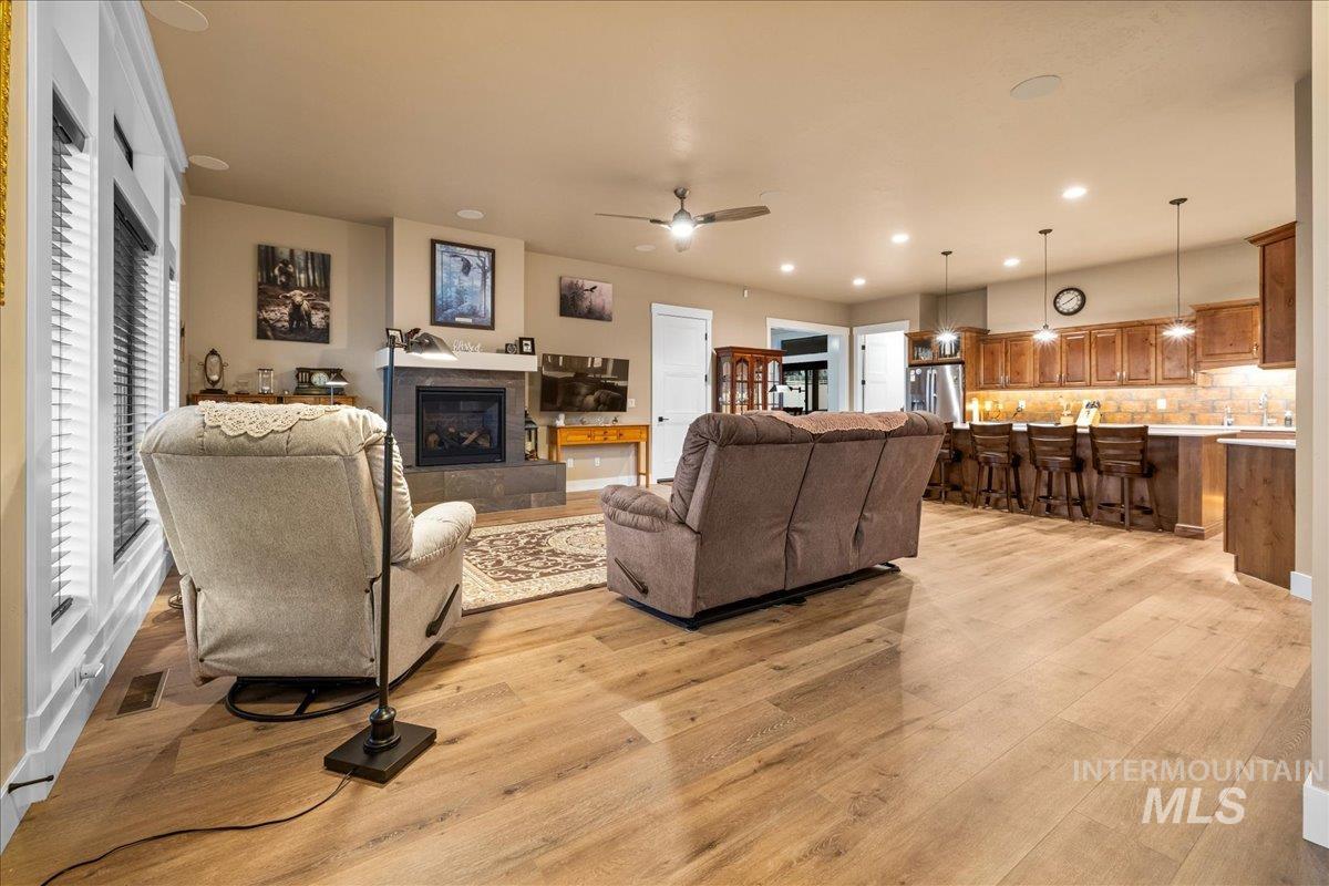 Living room with light wood finished floors, a fireplace, recessed lighting, and a ceiling fan