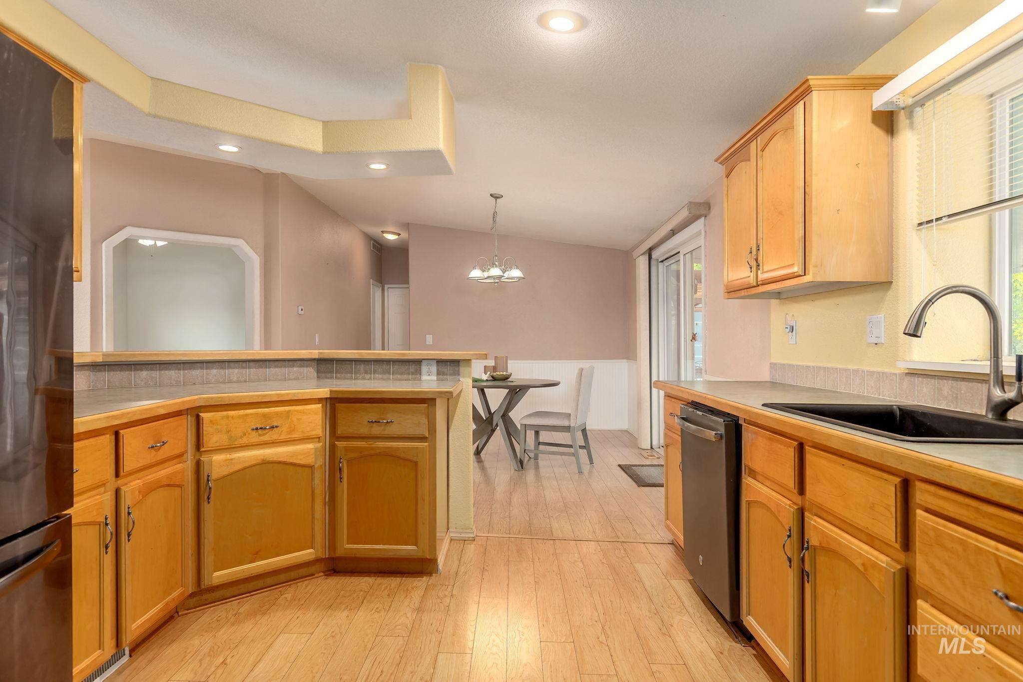 Kitchen featuring decorative light fixtures, a chandelier, light countertops, light wood-style flooring, and recessed lighting