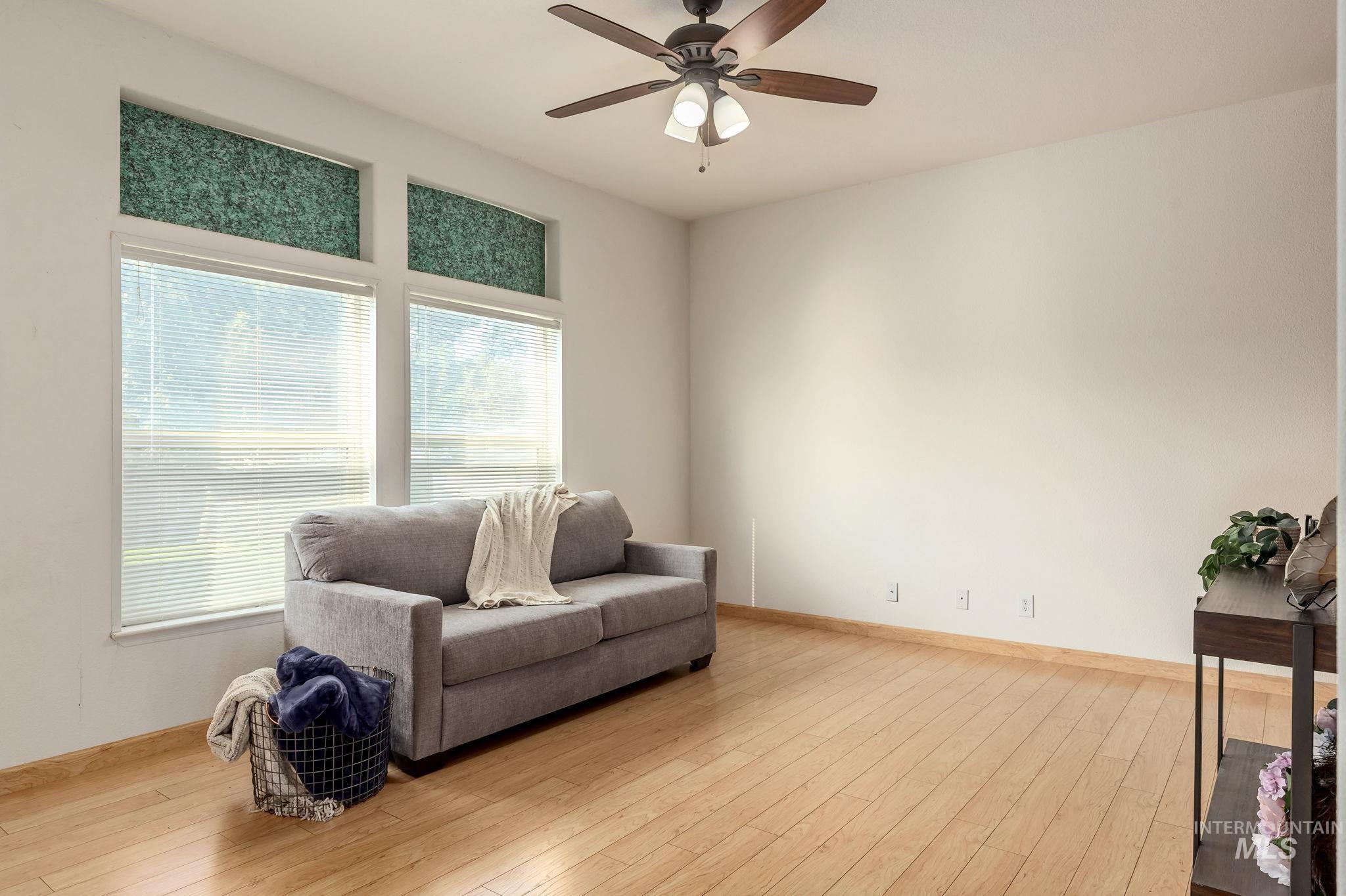 Sitting room with wood-type flooring and a ceiling fan