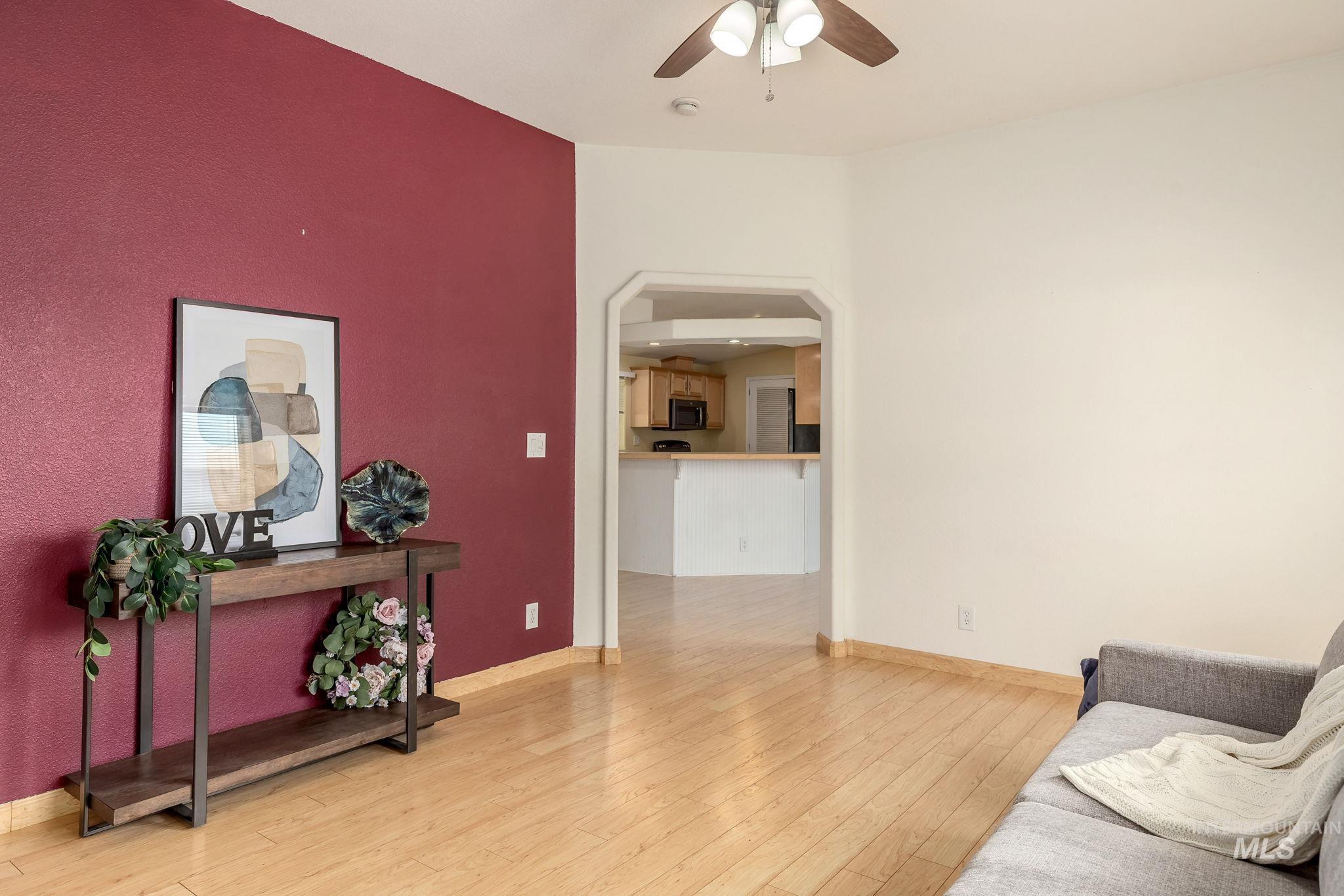 Sitting room featuring light wood finished floors, arched walkways, and a ceiling fan