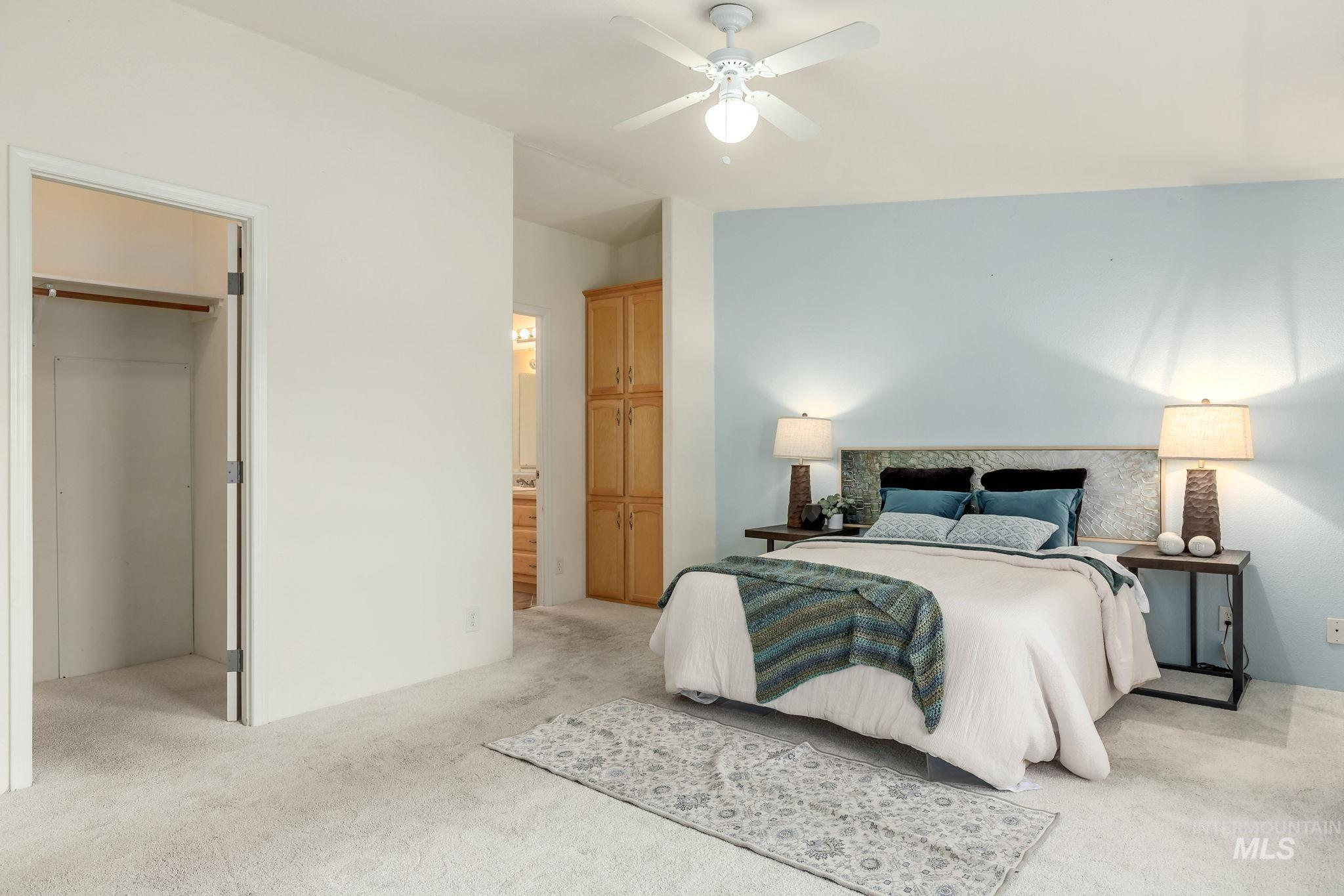 Bedroom with light carpet, a ceiling fan, a spacious closet, and connected bathroom