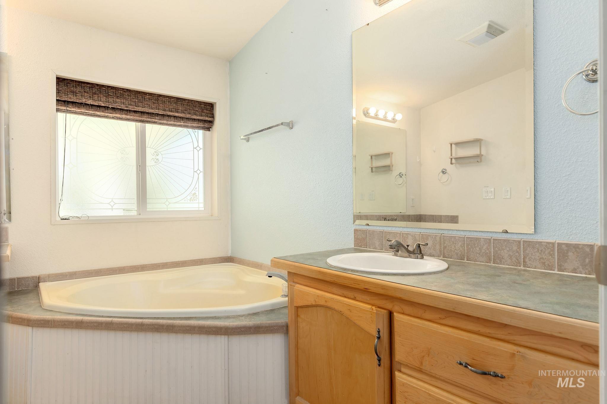 Bathroom featuring a garden tub and vanity
