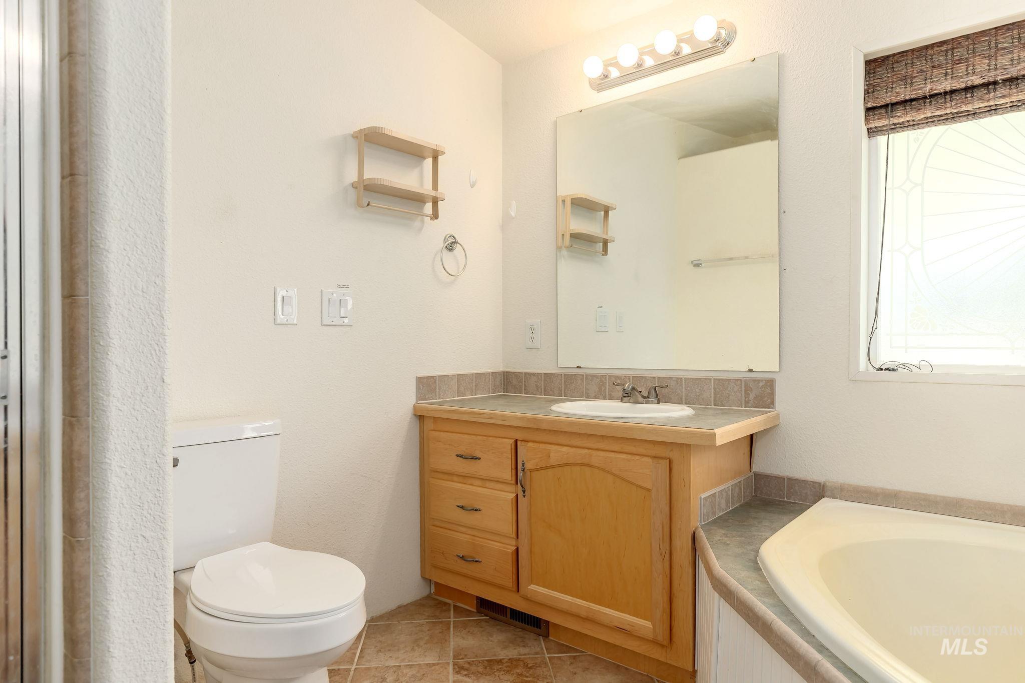 Bathroom with vanity, a bath, and light tile patterned floors