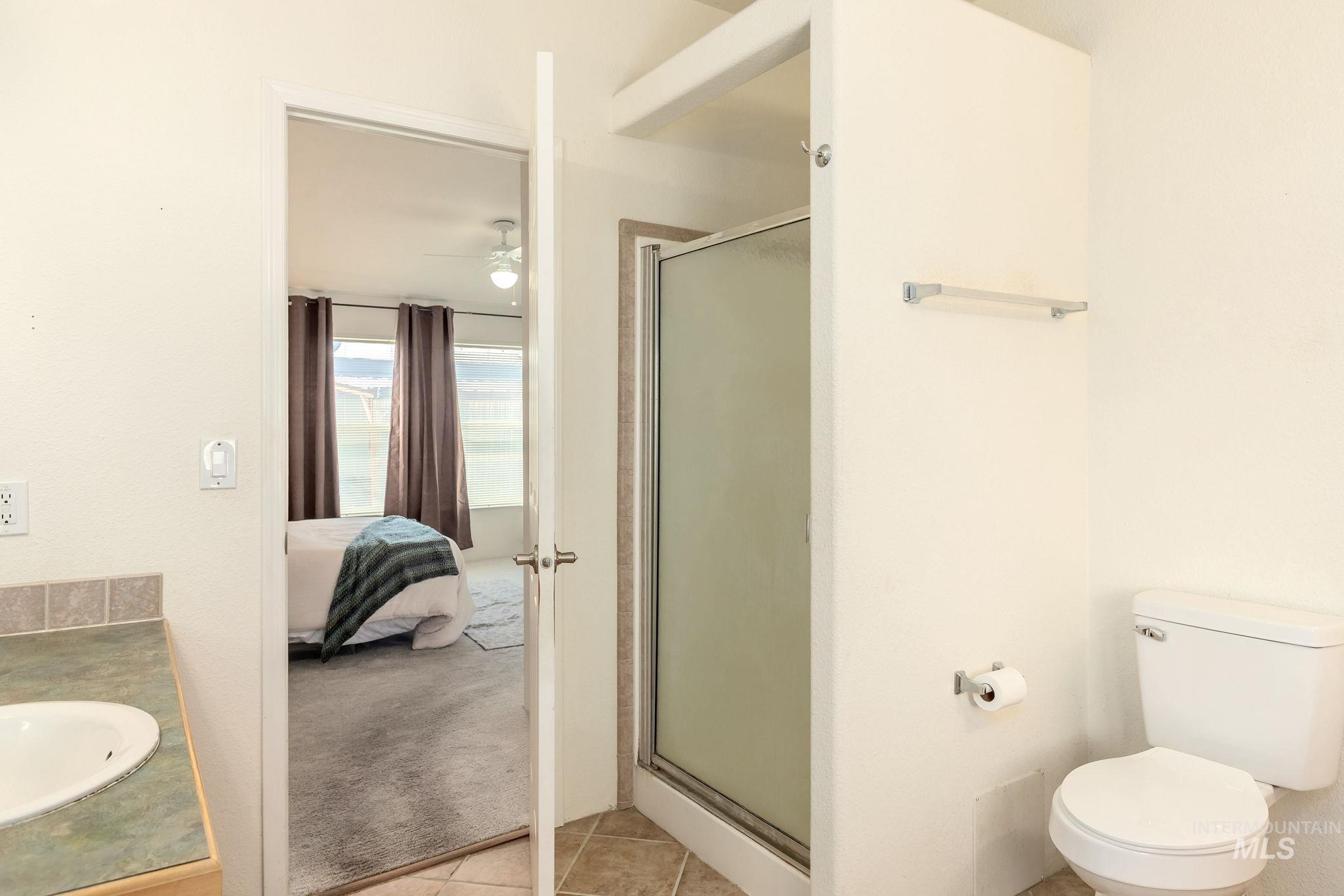 Full bathroom with a stall shower, ensuite bath, vanity, and light tile patterned floors