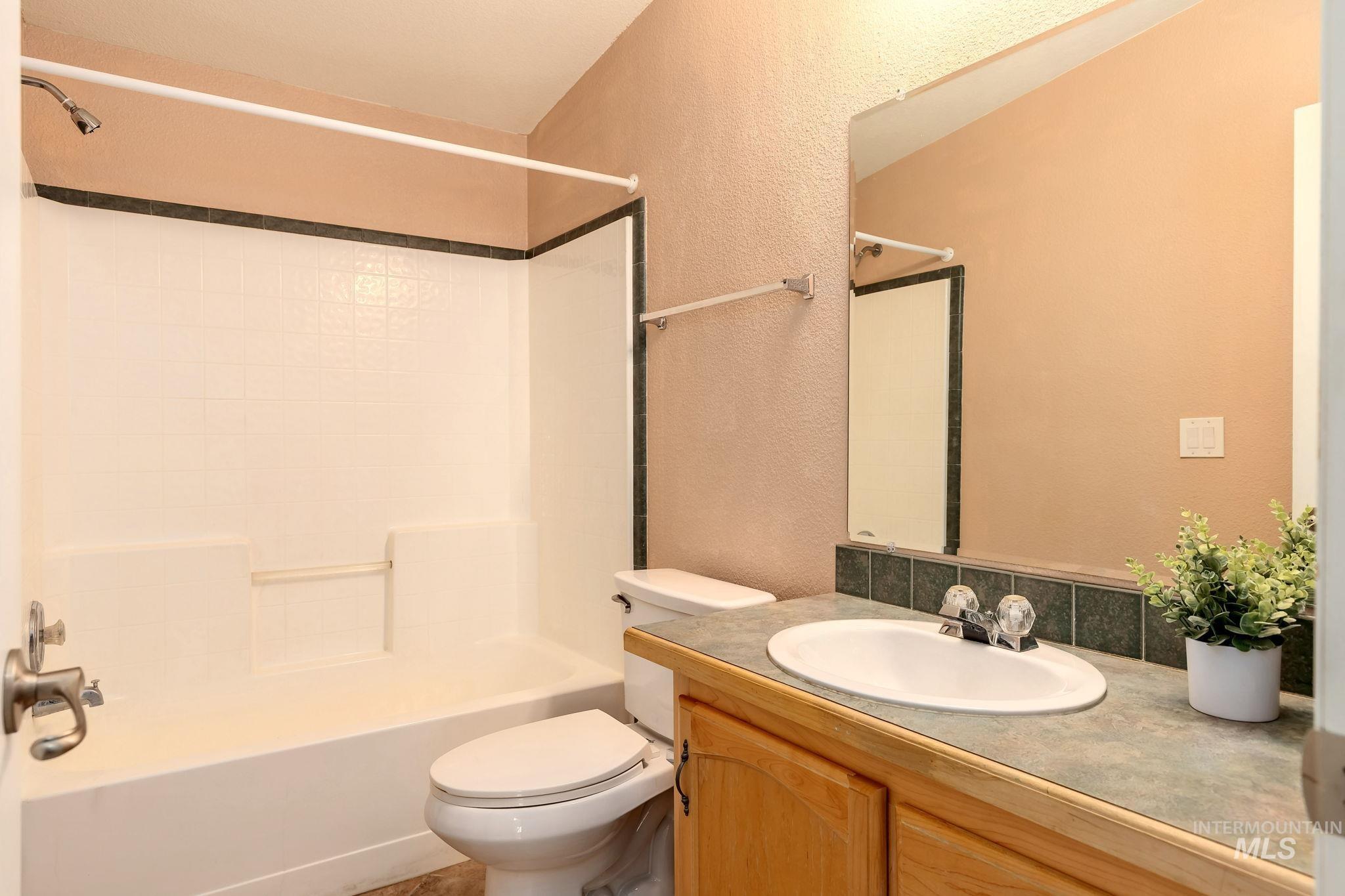 Bathroom featuring a textured wall, shower / washtub combination, and vanity