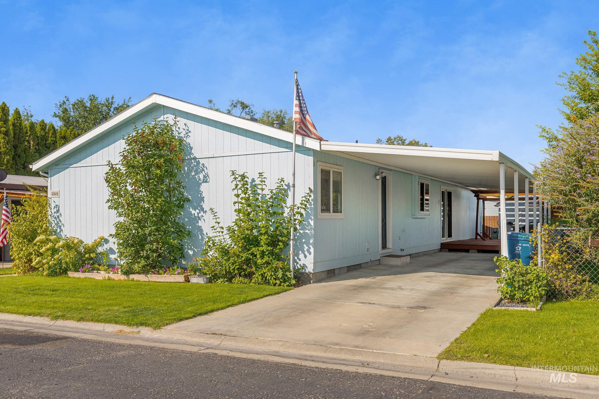 Manufactured / mobile home featuring a front yard, an attached carport, and driveway