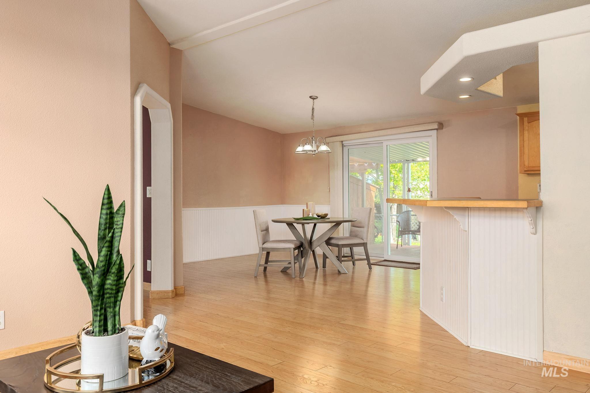 Living room with light wood-style floors, a chandelier, recessed lighting, and a wainscoted wall