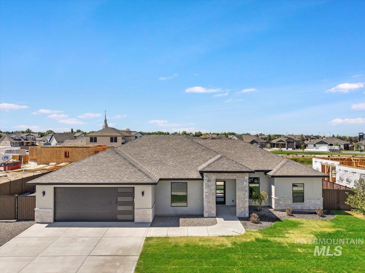 View of front facade featuring stone siding, a shingled roof, stucco siding, an attached garage, and driveway