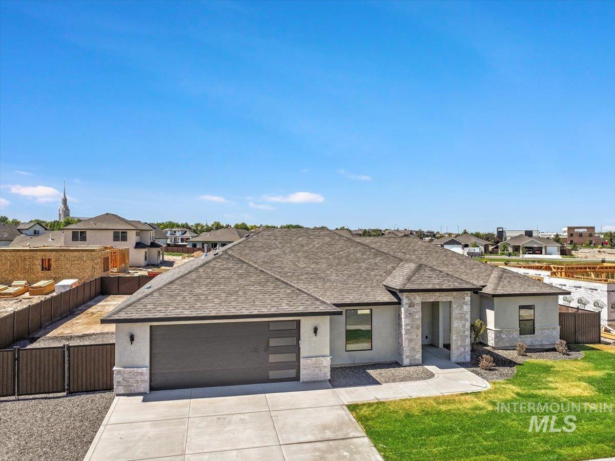 View of front of home featuring roof with shingles, a garage, a residential view, stone siding, and concrete driveway