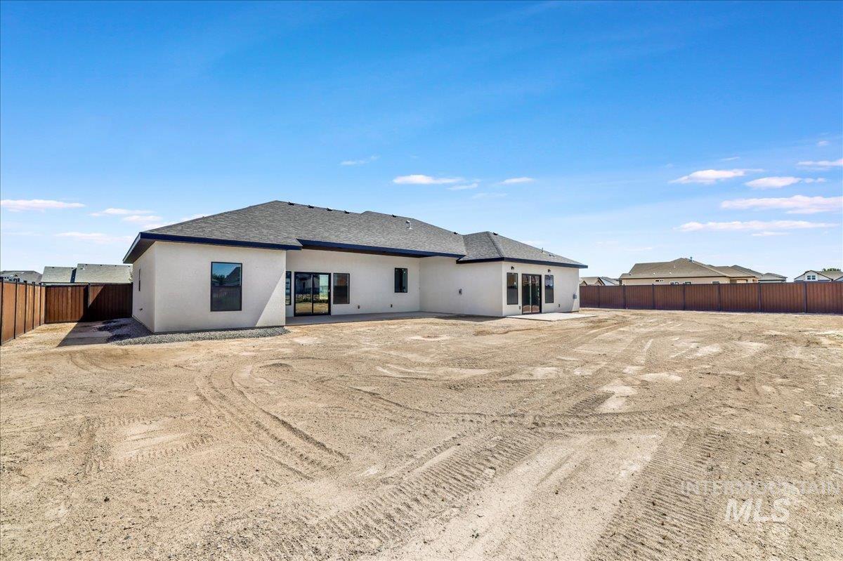 Back of house with a fenced backyard, stucco siding, a patio area, and roof with shingles