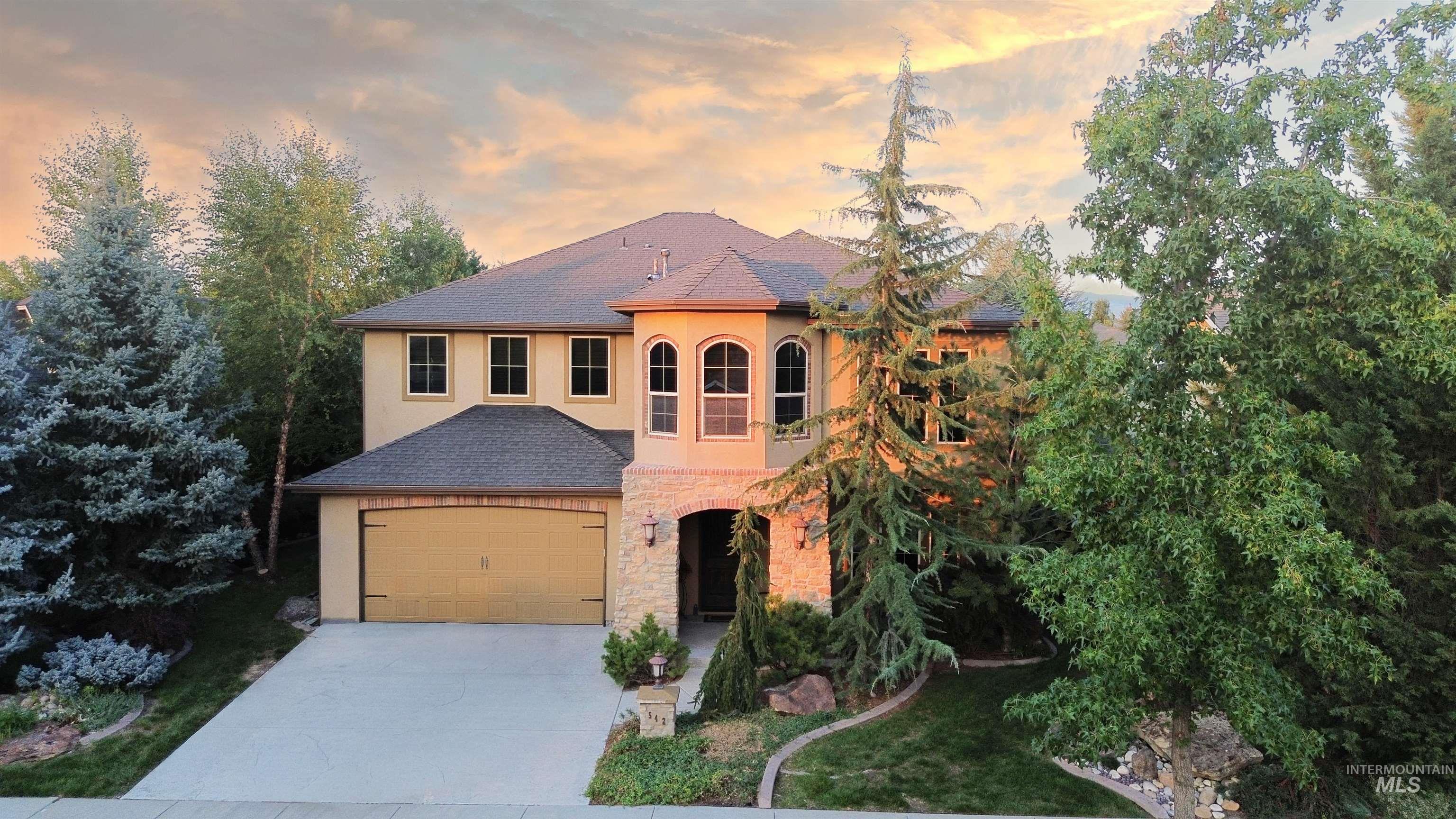 Mediterranean / spanish-style house with driveway, a shingled roof, stucco siding, stone siding, and an attached garage