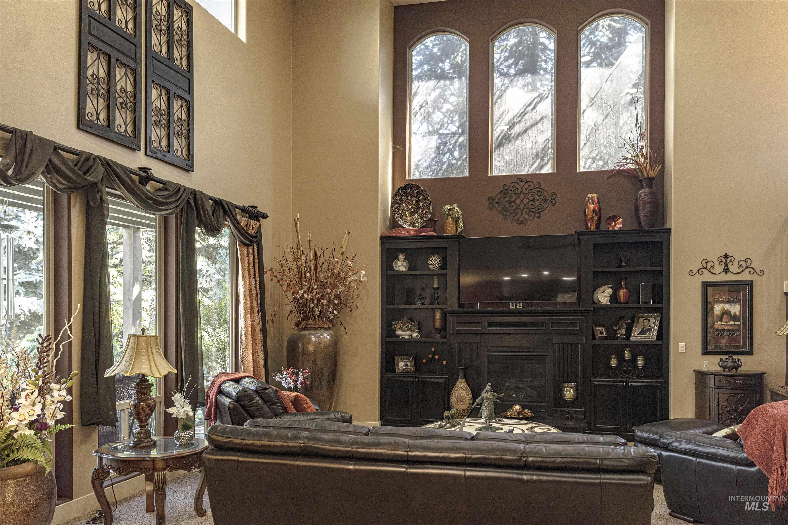 Carpeted living room featuring a towering ceiling and a glass covered fireplace