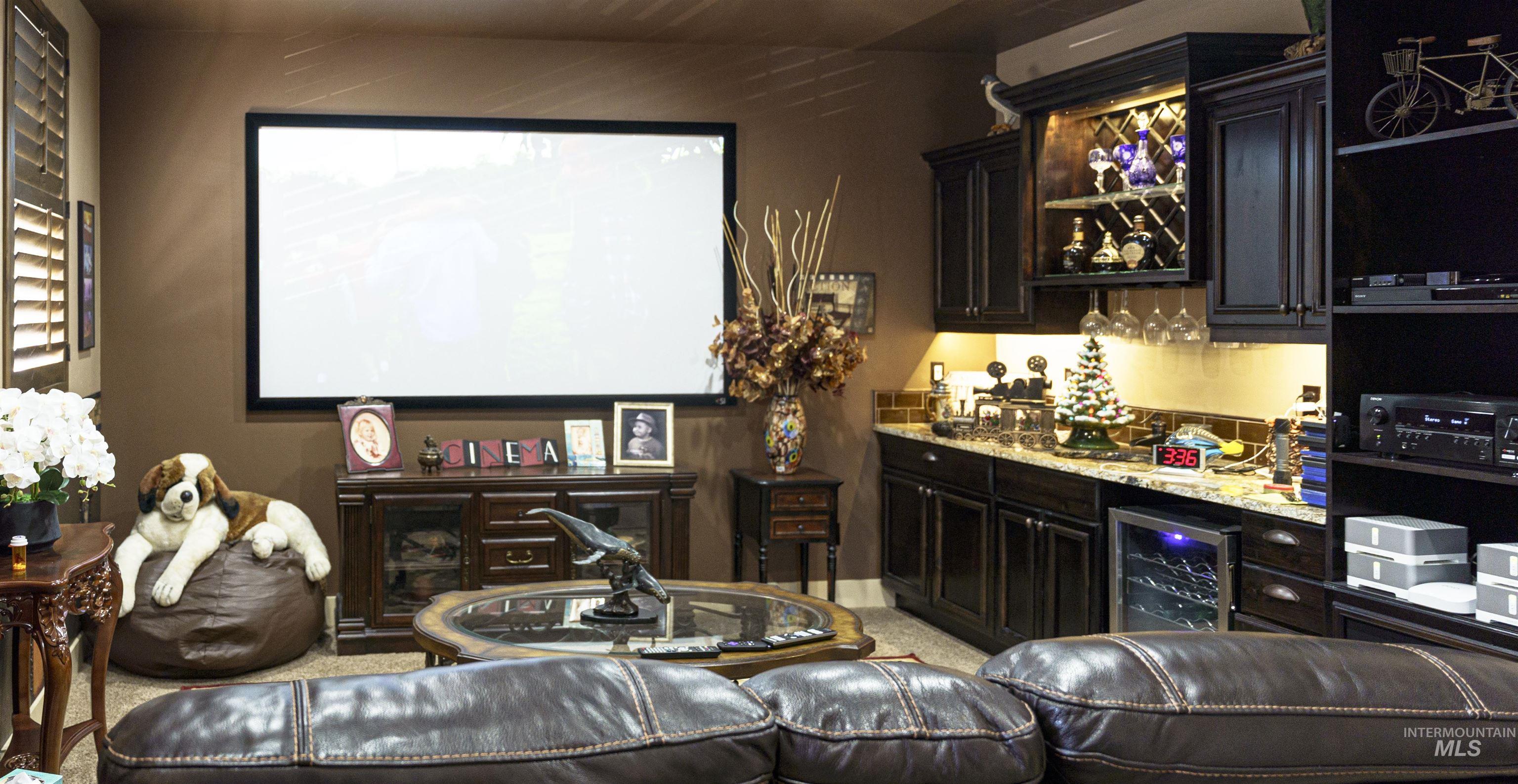 Home theater room featuring bar, beverage cooler, and light carpet