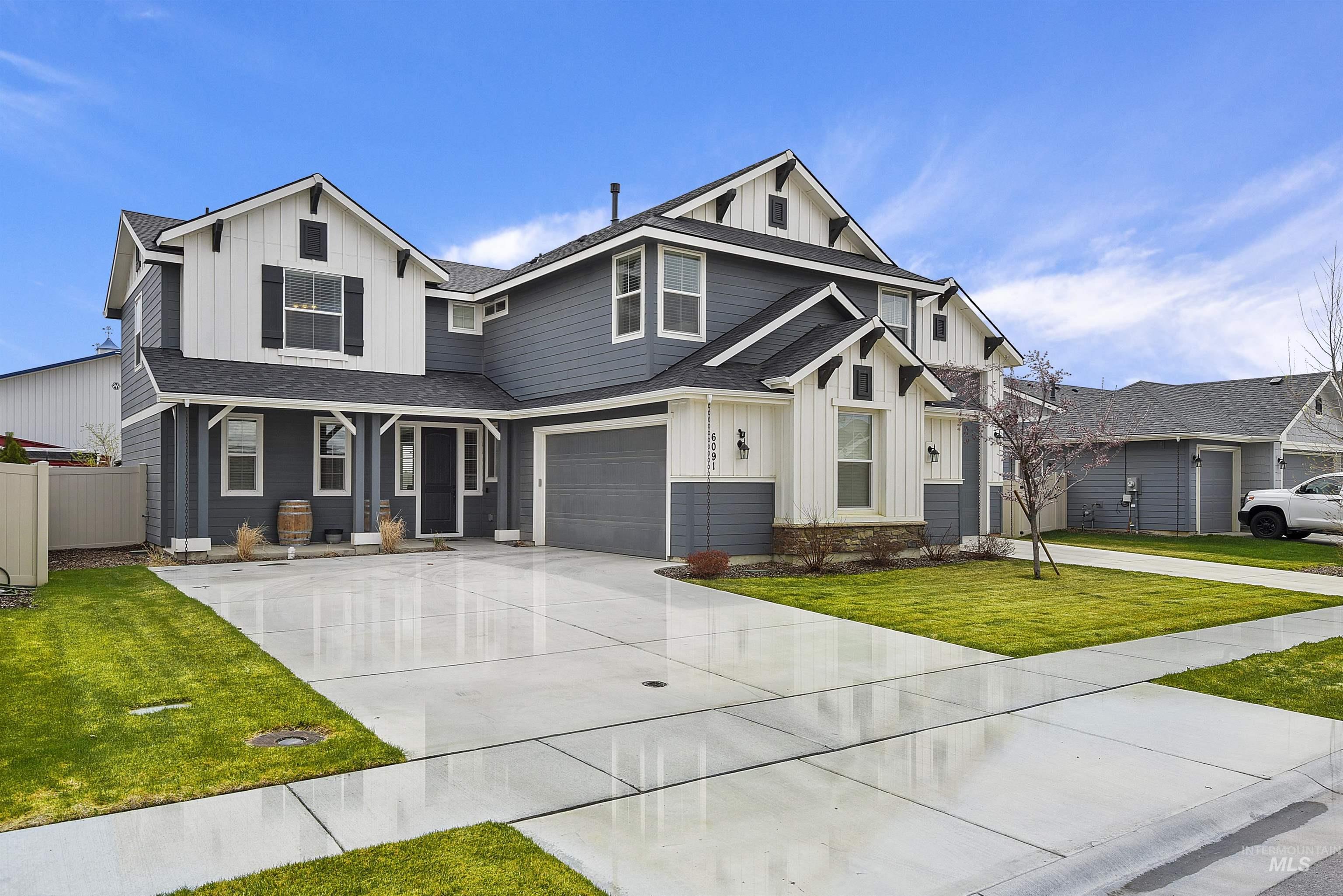View of front facade featuring board and batten siding, concrete driveway, a shingled roof, covered porch, and a garage