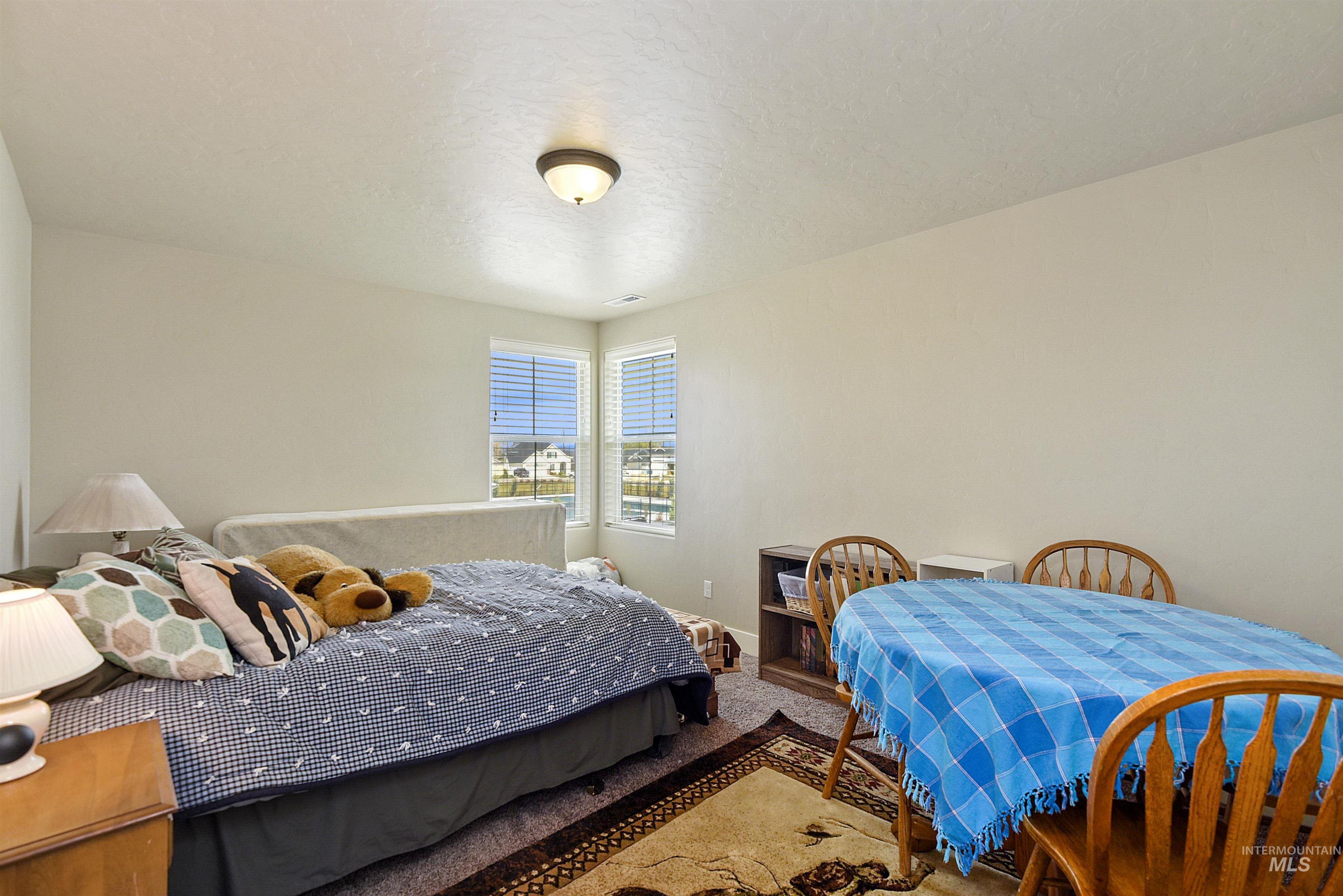 Carpeted bedroom featuring a textured ceiling and baseboards