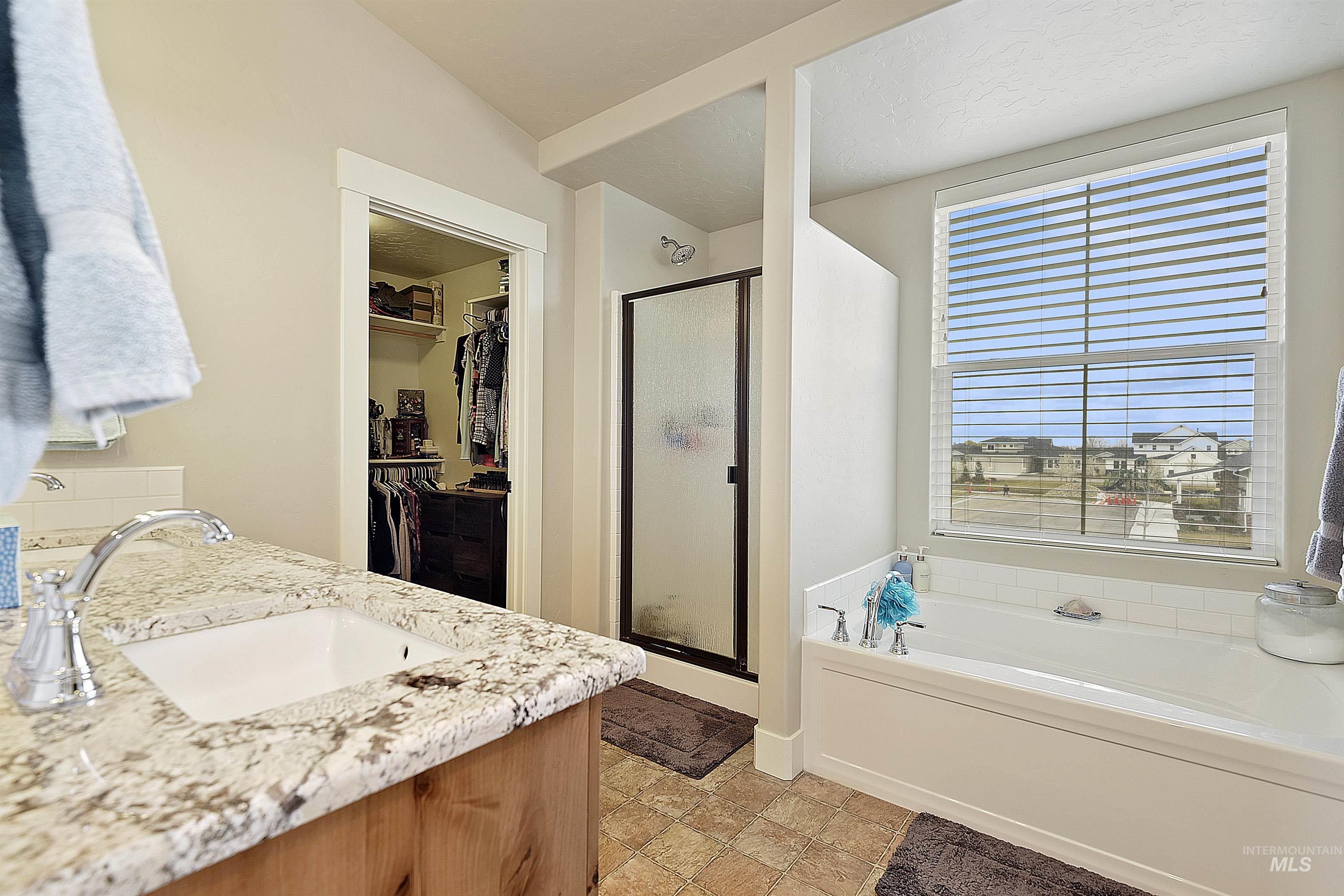 Bathroom with a spacious closet, vanity, a shower stall, and a bath