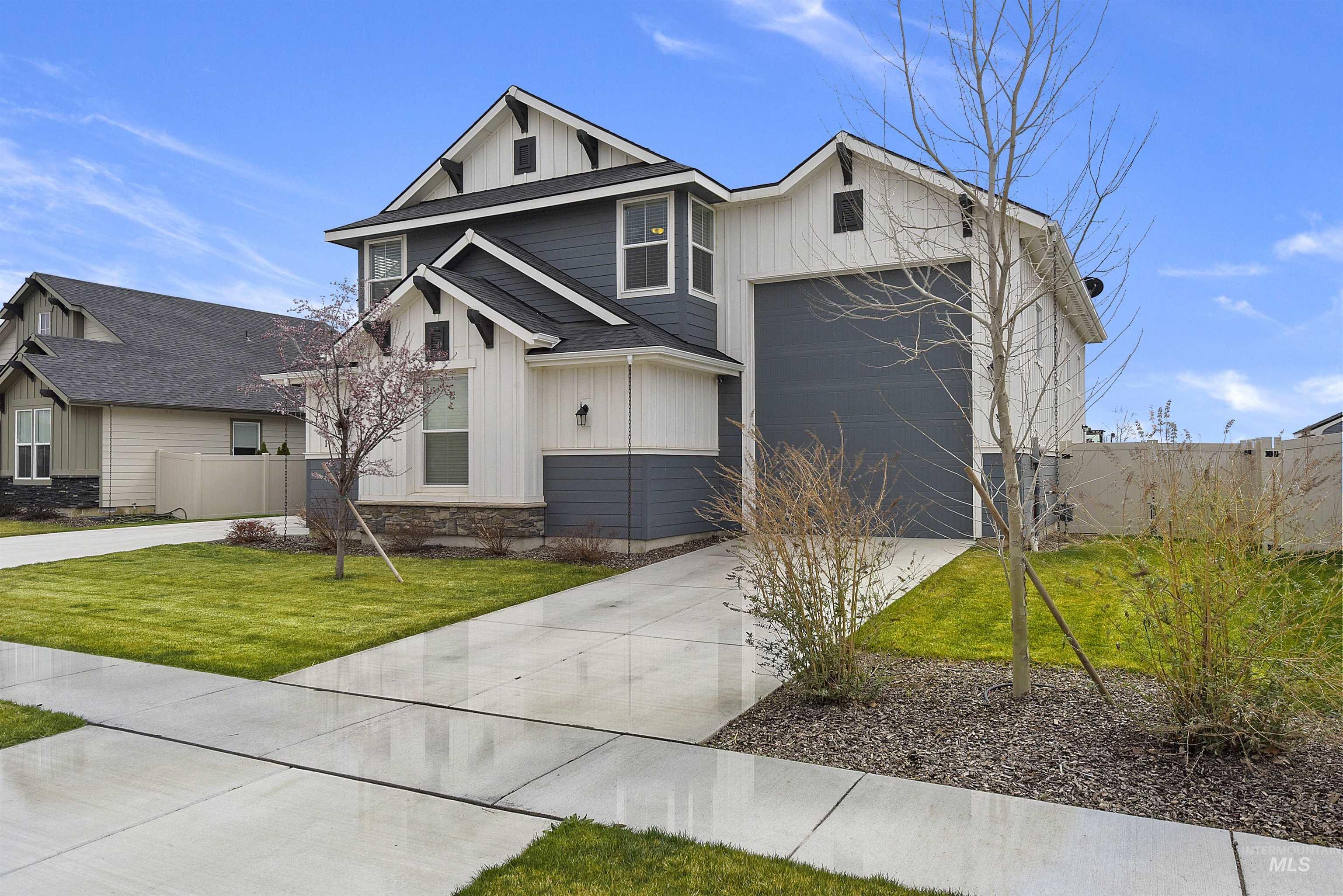View of front of property featuring board and batten siding, concrete driveway, stone siding, and a garage