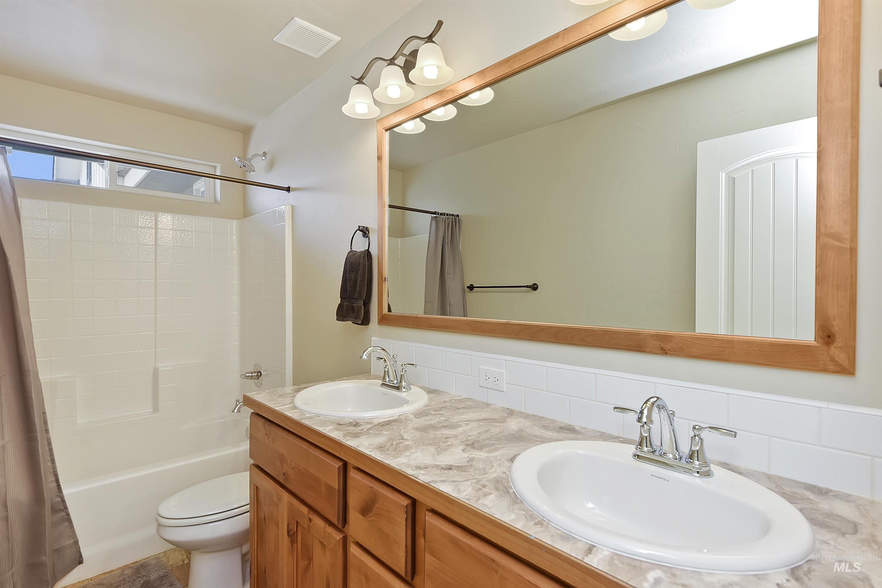 Full bathroom with shower / tub combo, double vanity, and decorative backsplash