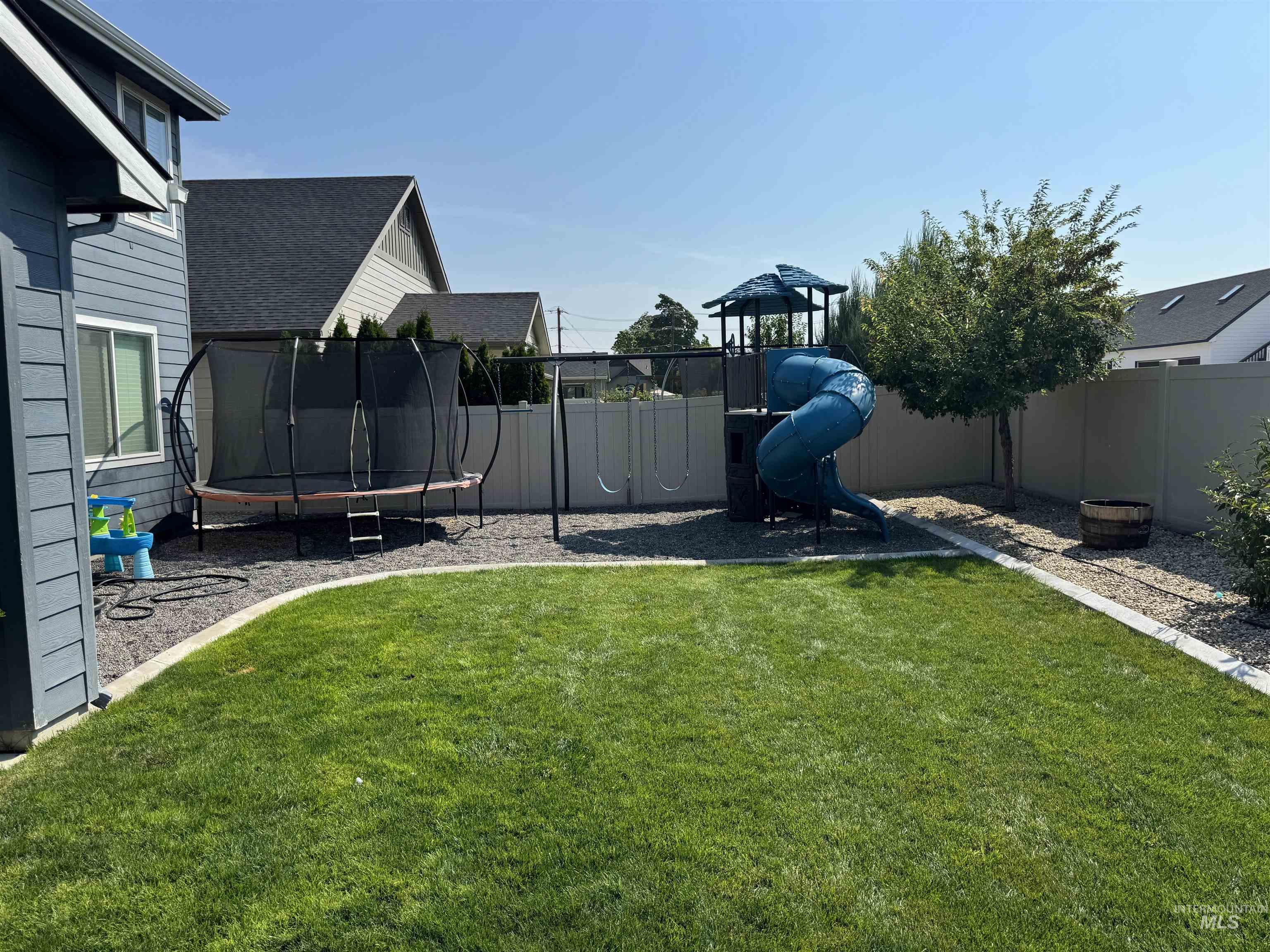 View of yard with a trampoline and a playground