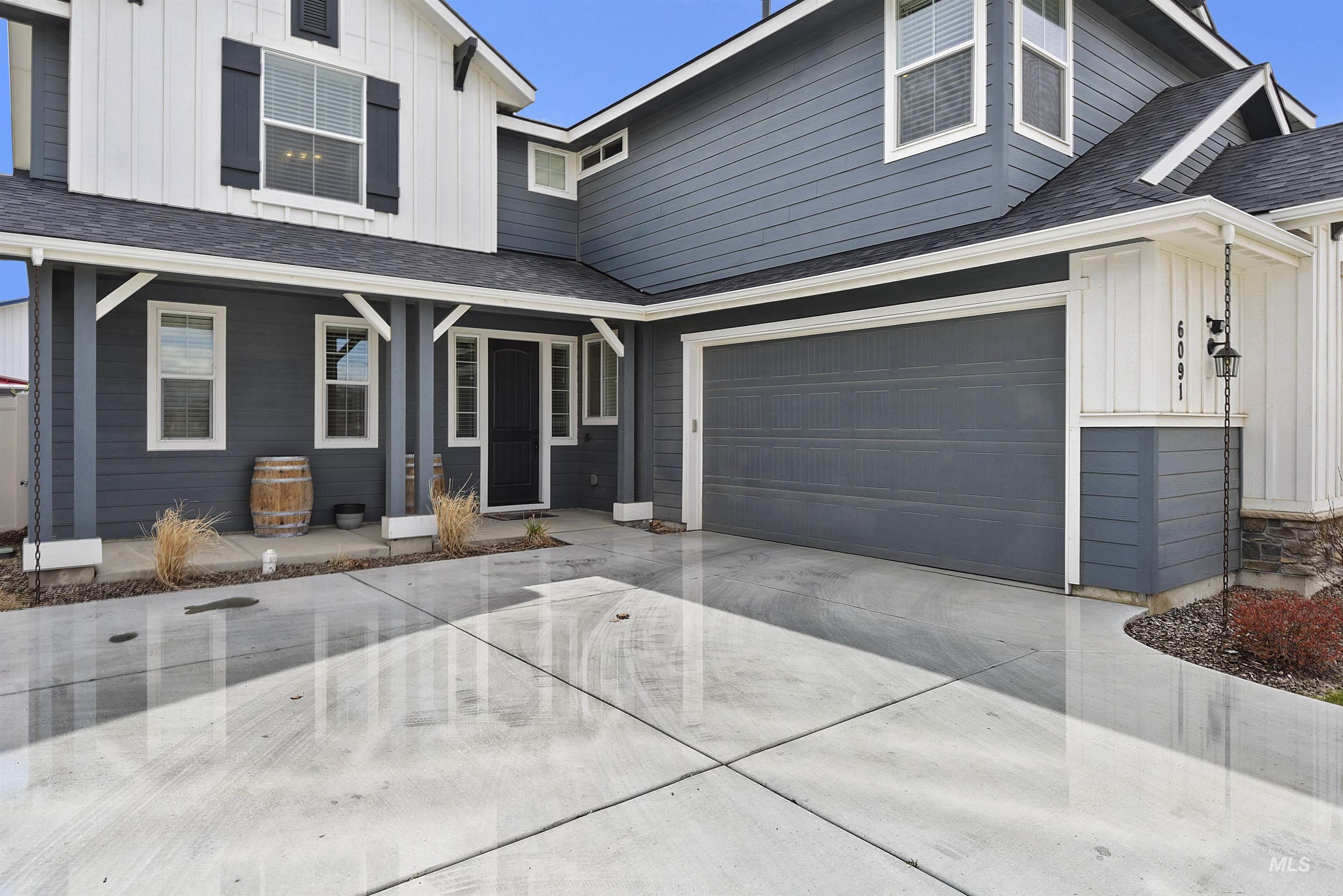 View of front of property with board and batten siding, a shingled roof, an attached garage, a porch, and concrete driveway