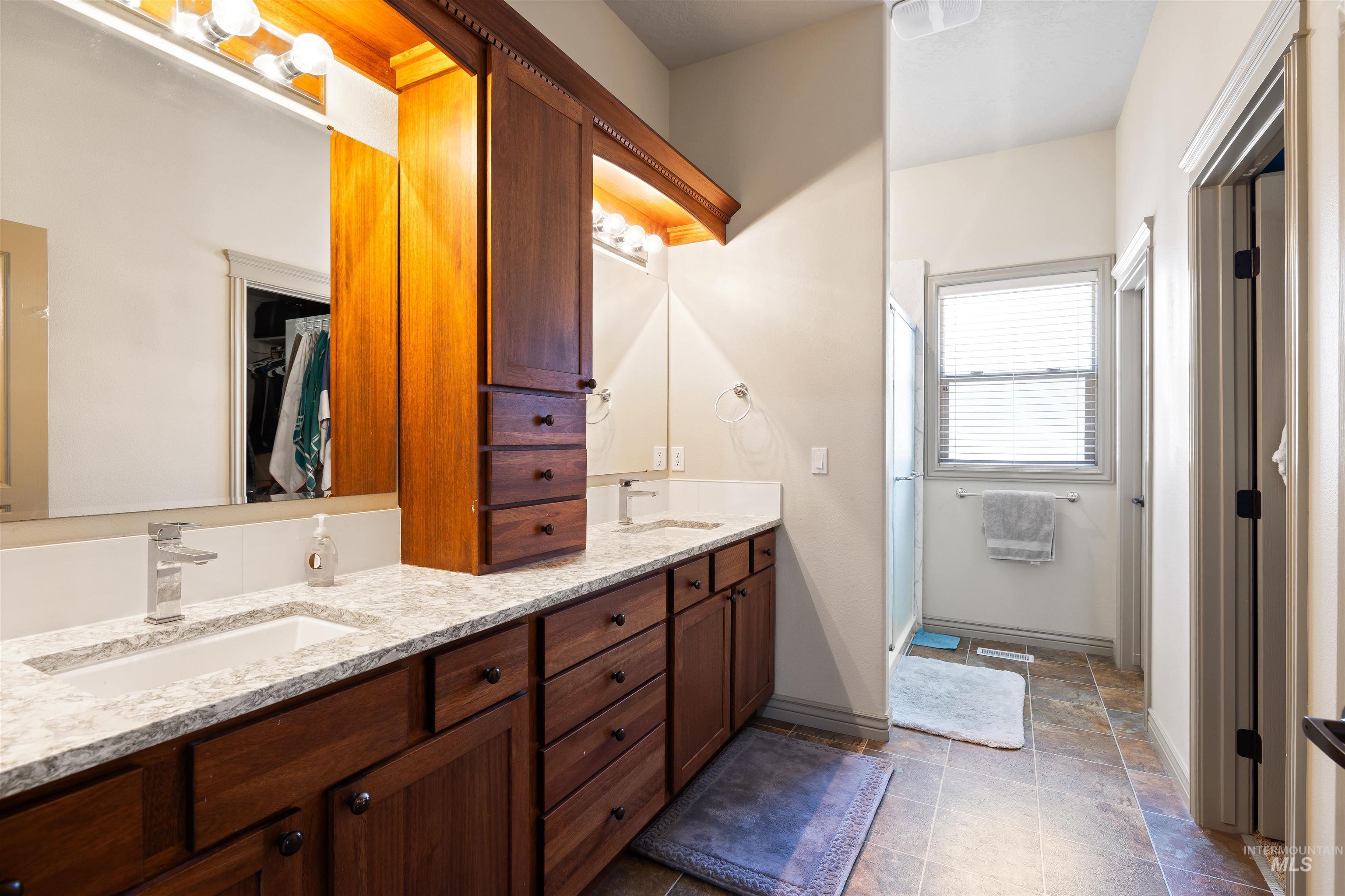 Full bath featuring double vanity, a stall shower, and a spacious closet