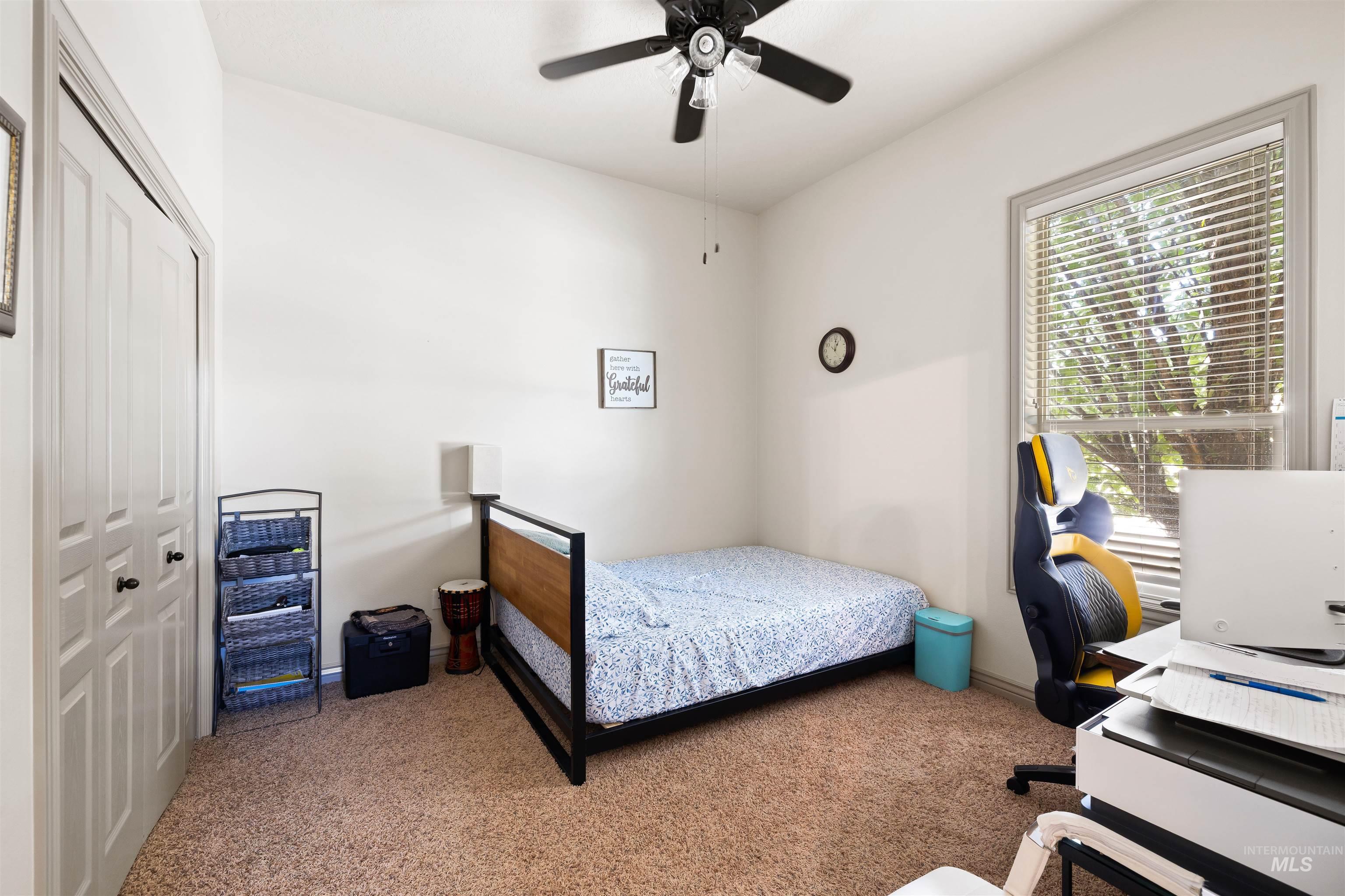 Carpeted bedroom featuring a closet, a ceiling fan, and an office area
