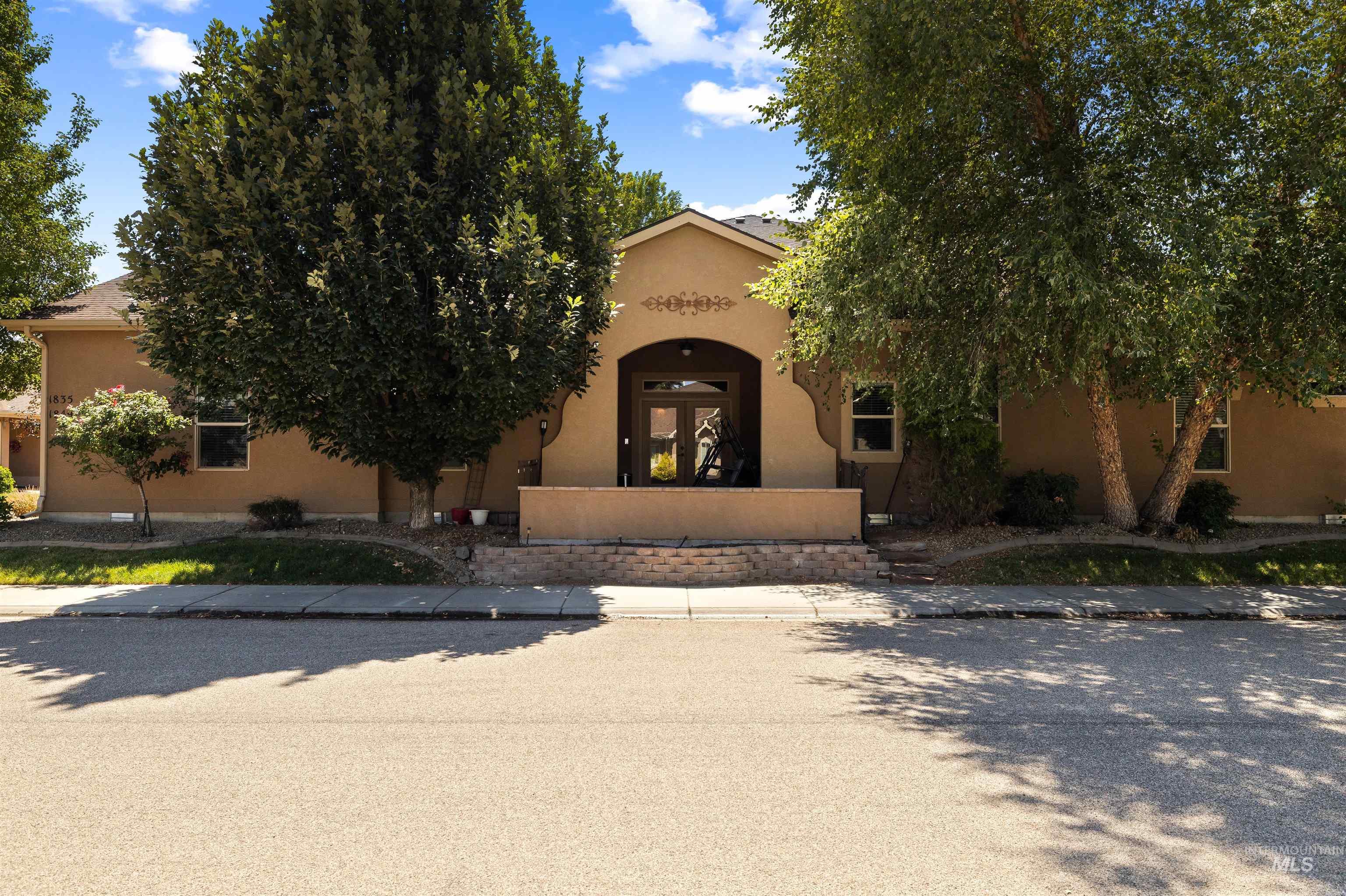 View of property hidden behind natural elements featuring stucco siding