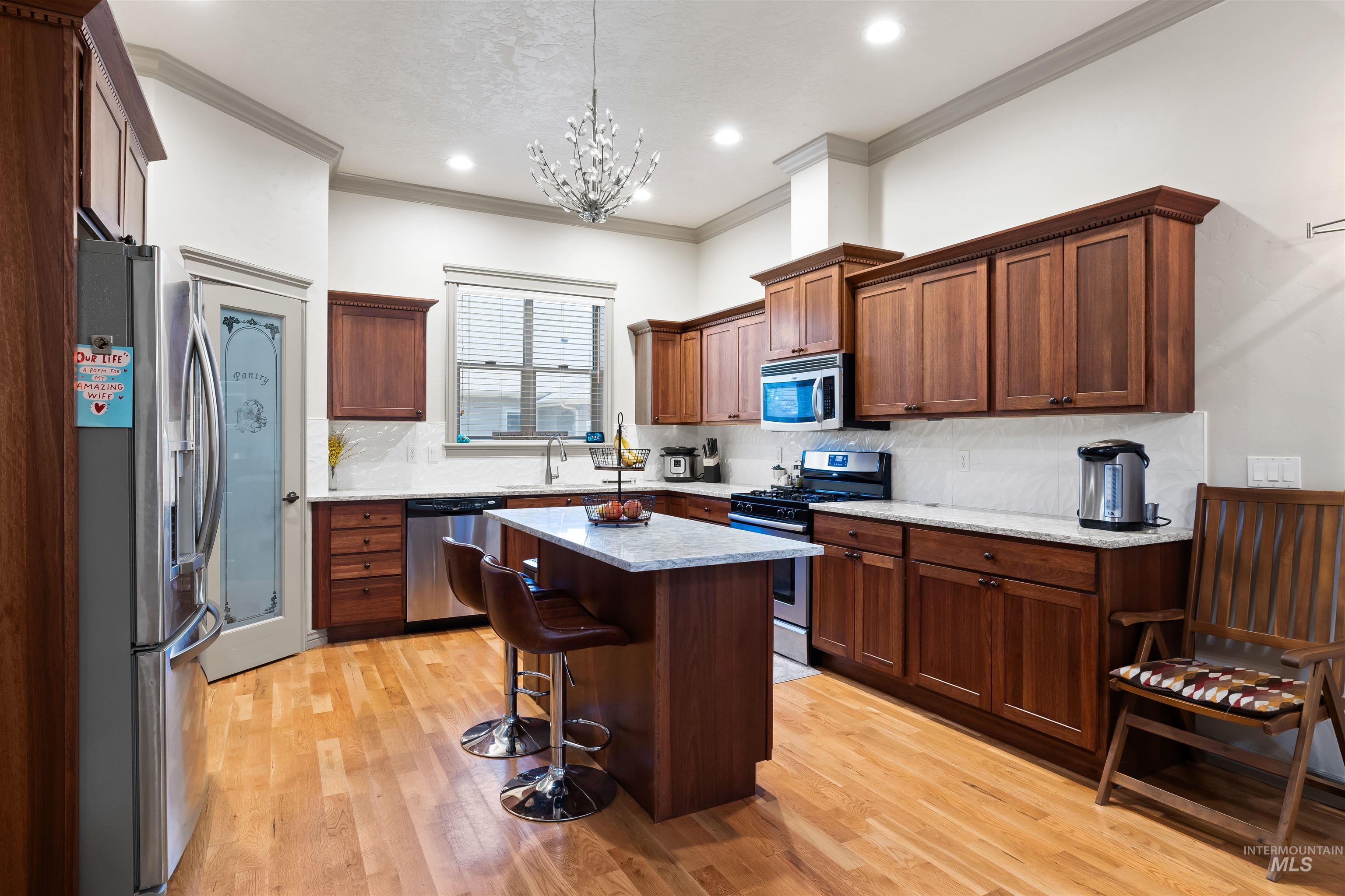 Kitchen featuring appliances with stainless steel finishes, a breakfast bar, decorative backsplash, light wood finished floors, and a center island