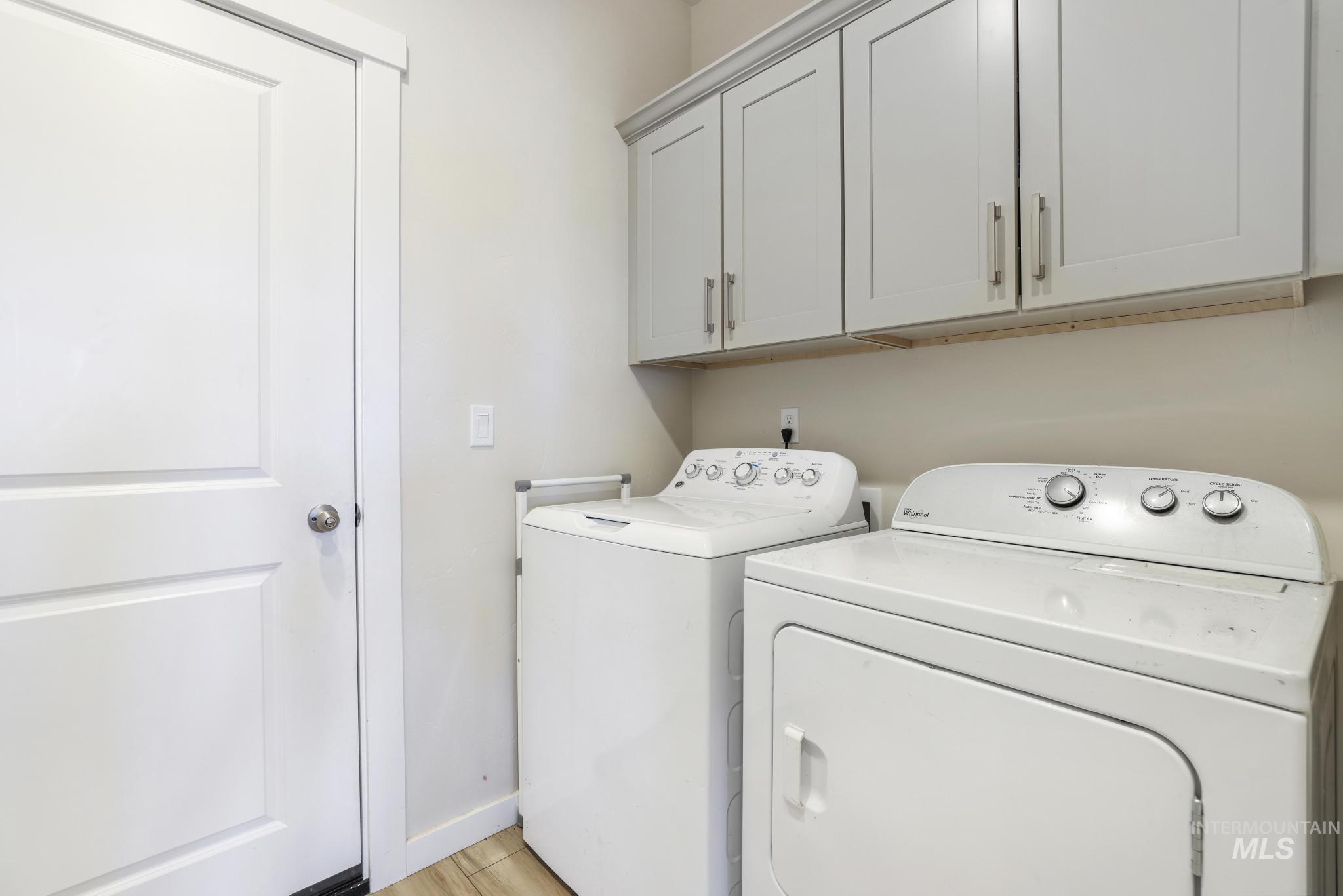 Laundry area featuring independent washer and dryer and cabinet space