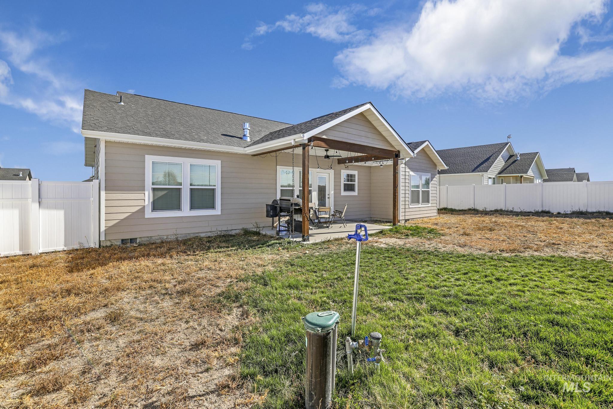 Rear view of property with a patio area, a fenced backyard, and a shingled roof