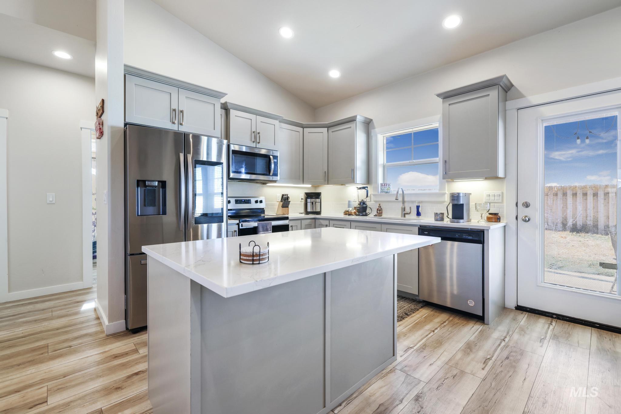 Kitchen featuring gray cabinets, stainless steel appliances, recessed lighting, a center island, and light wood-style flooring