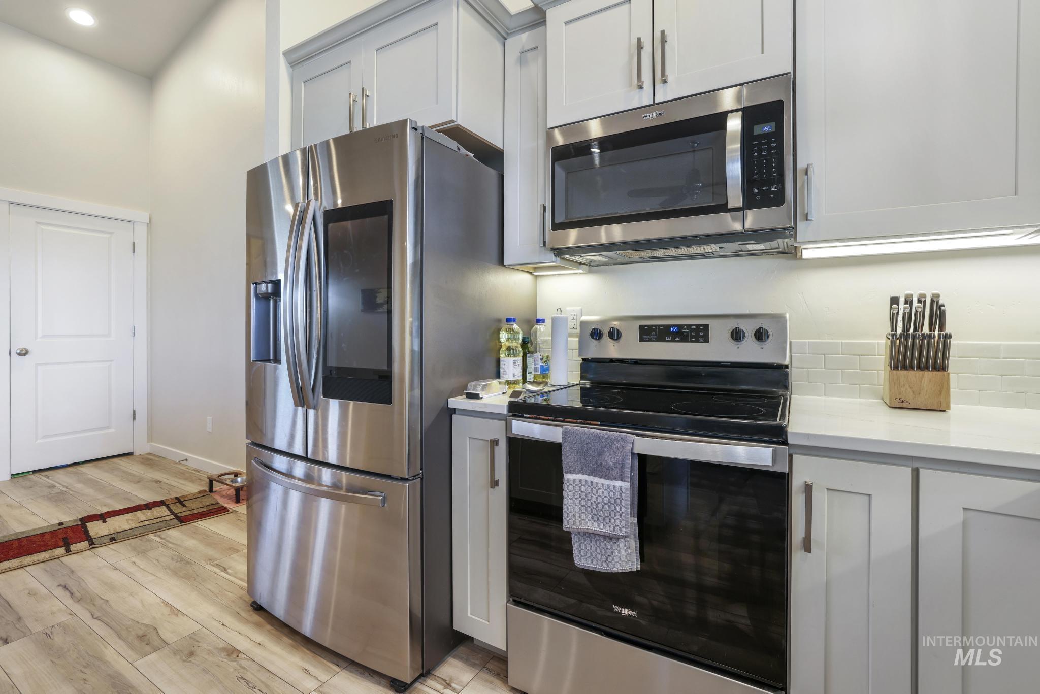 Kitchen featuring stainless steel appliances, light wood-type flooring, and light stone countertops