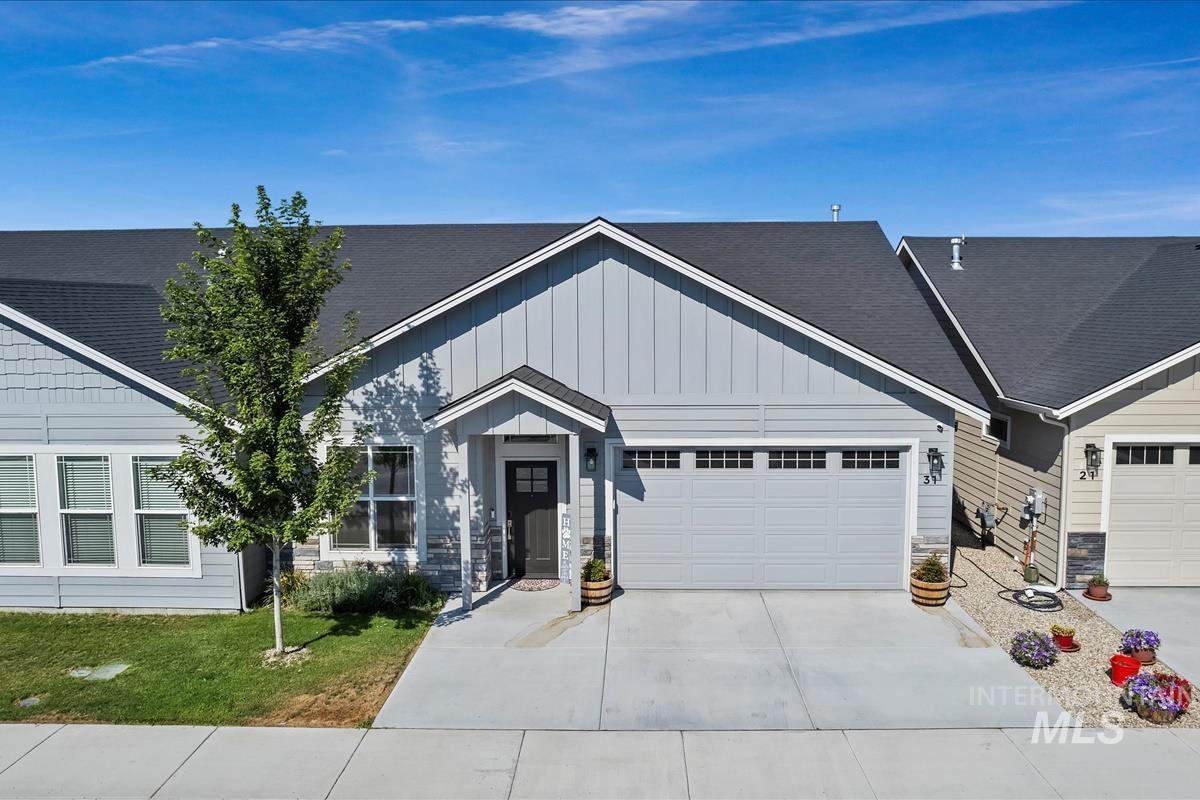 View of front of property with roof with shingles, concrete driveway, stone siding, a garage, and board and batten siding