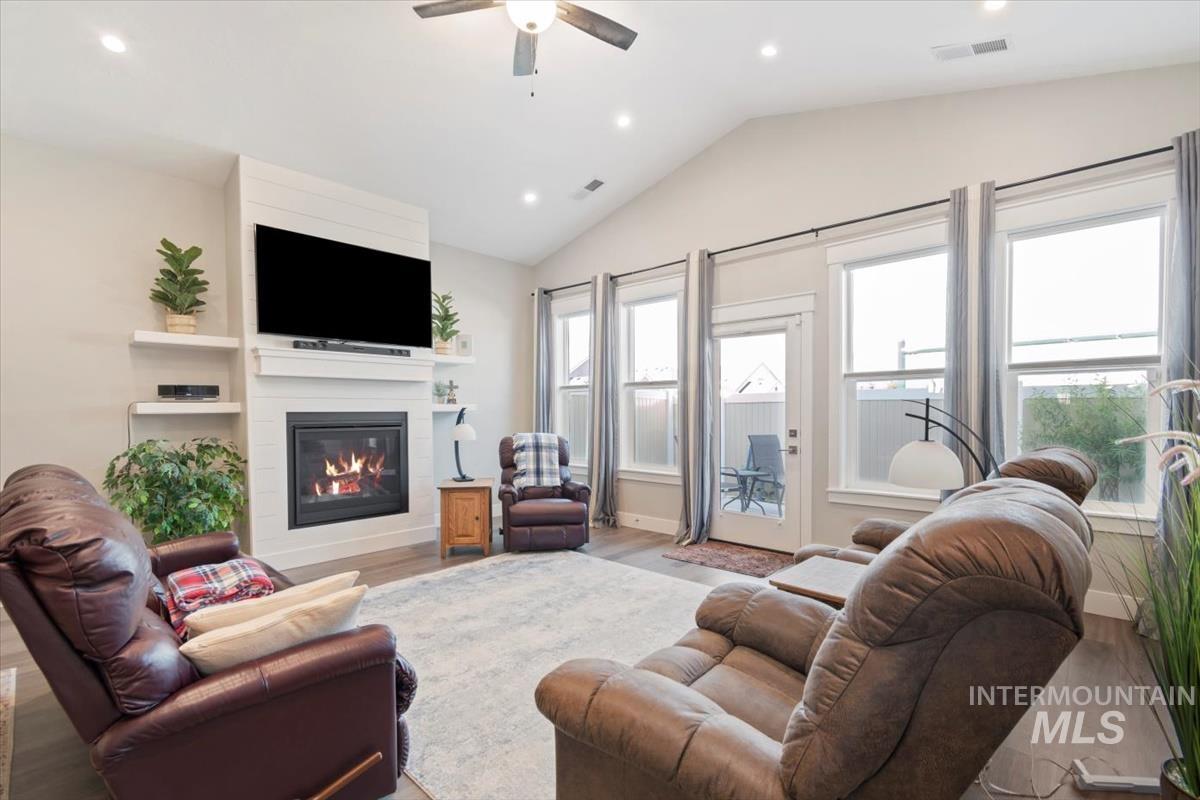 Living area featuring recessed lighting, a large fireplace, wood finished floors, lofted ceiling, and ceiling fan