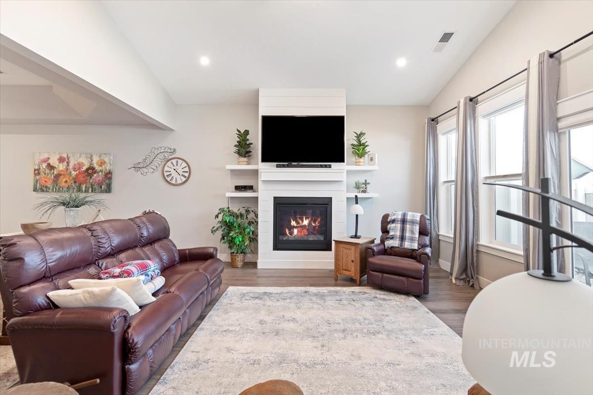 Living area with wood finished floors, a large fireplace, recessed lighting, and lofted ceiling