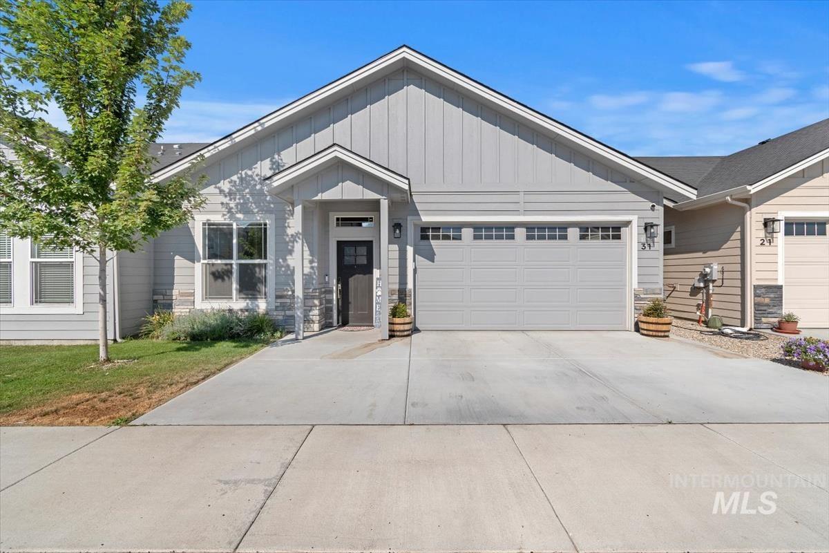 View of front of house featuring board and batten siding, concrete driveway, an attached garage, and stone siding