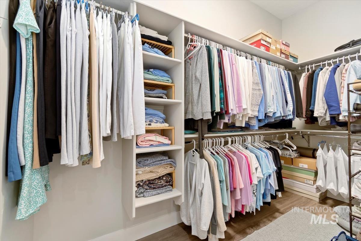Primary Walk in closet with dark wood-type flooring