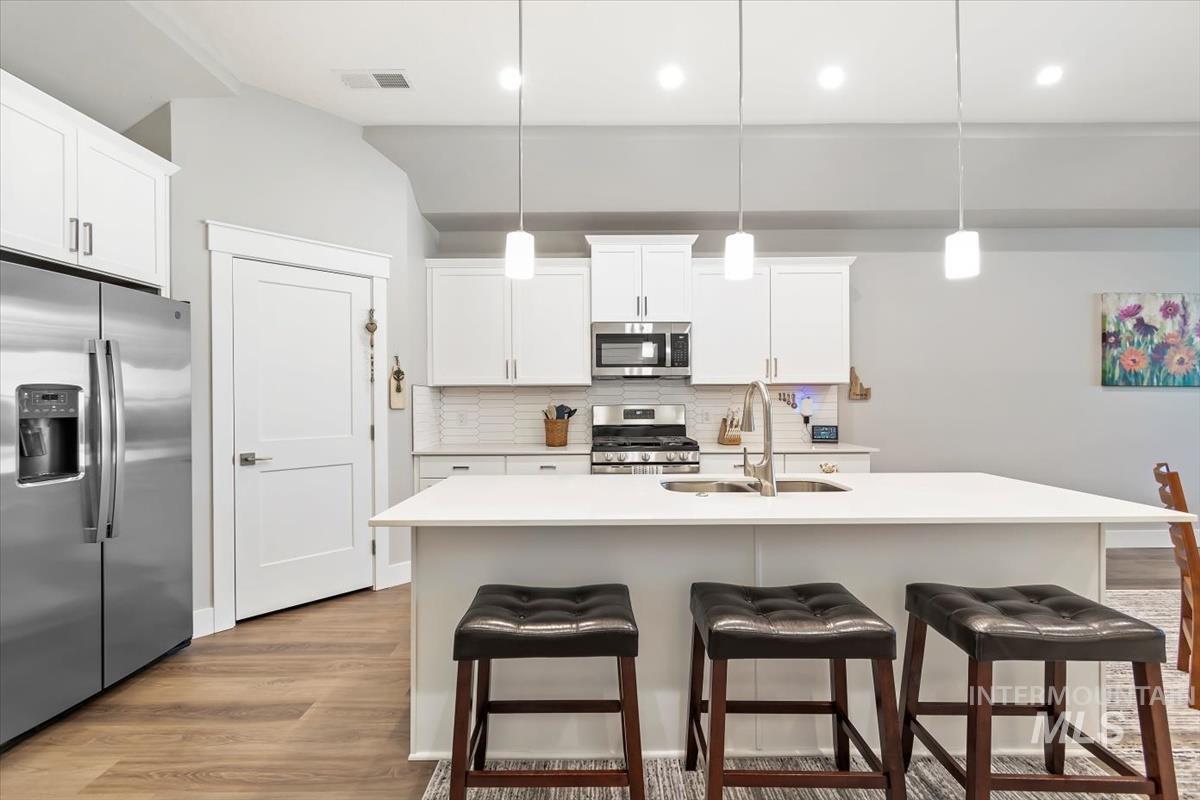 Kitchen featuring stainless steel appliances, tasteful backsplash, hanging light fixtures, a kitchen breakfast bar, and recessed lighting