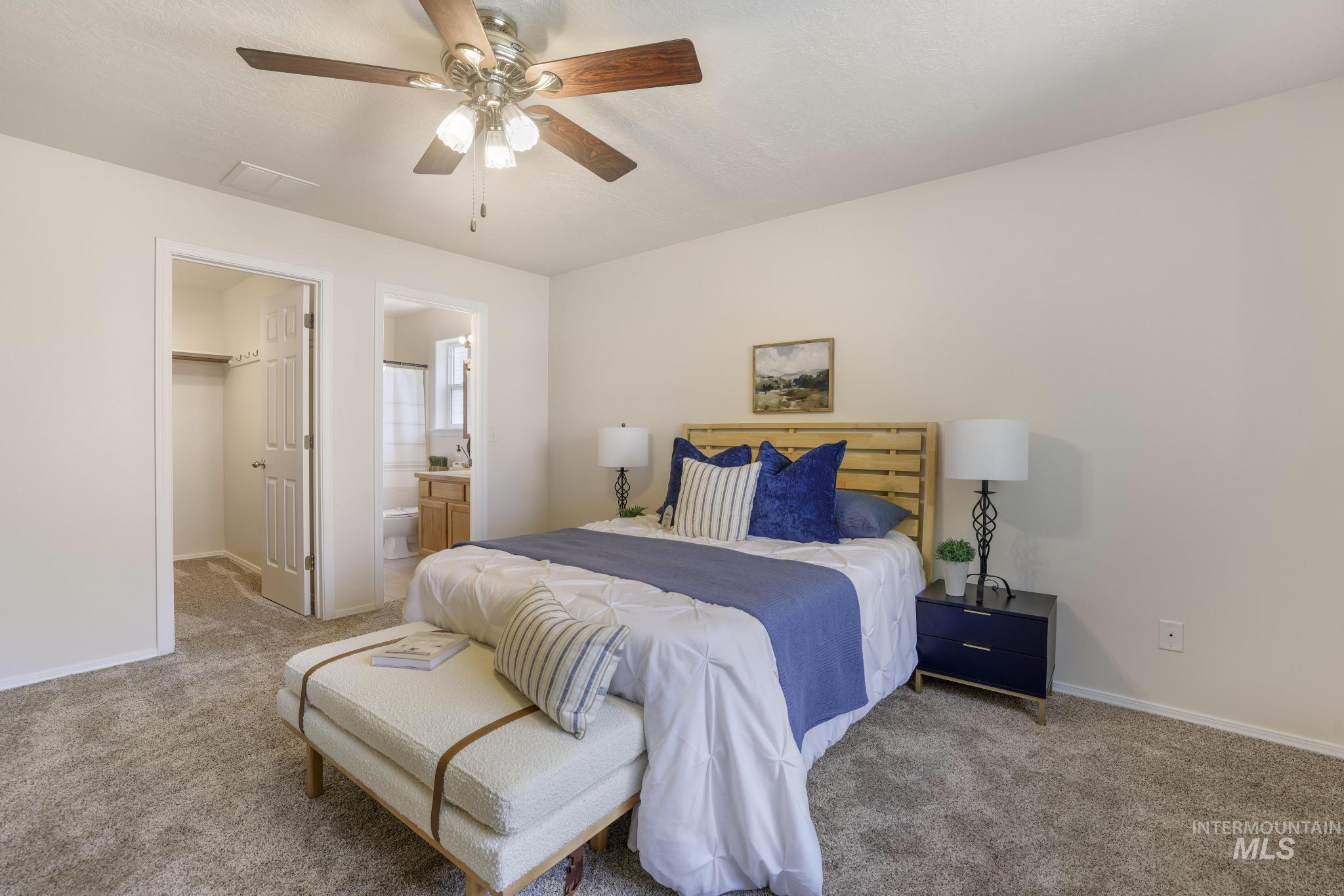 Bedroom with a walk in closet, carpet flooring, ceiling fan, and connected bathroom