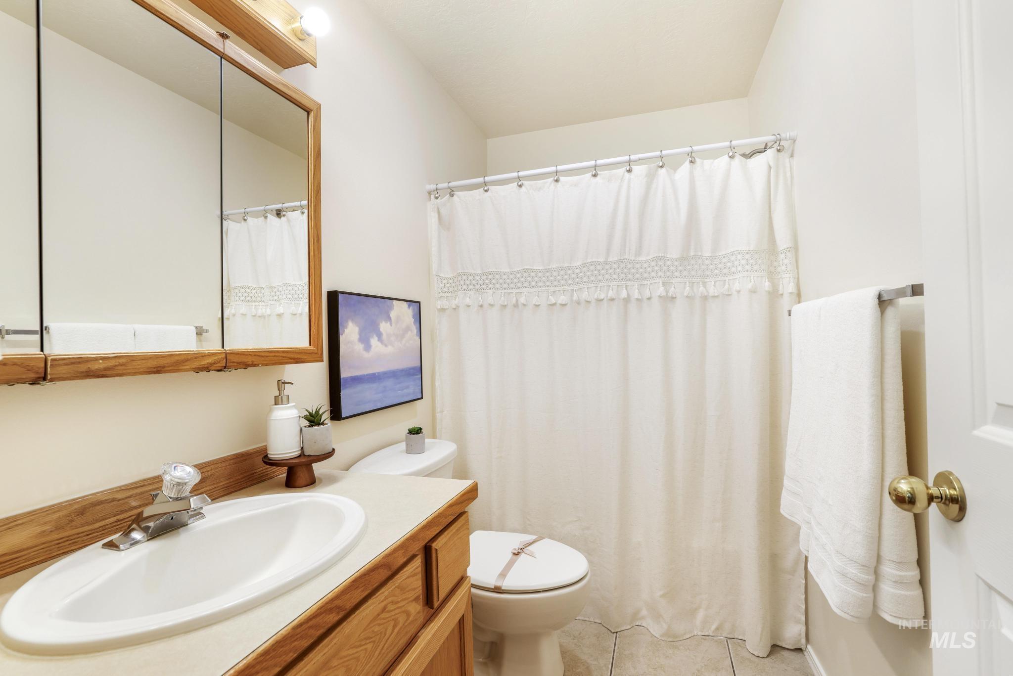 Bathroom with vanity, light tile patterned flooring, and a shower with curtain
