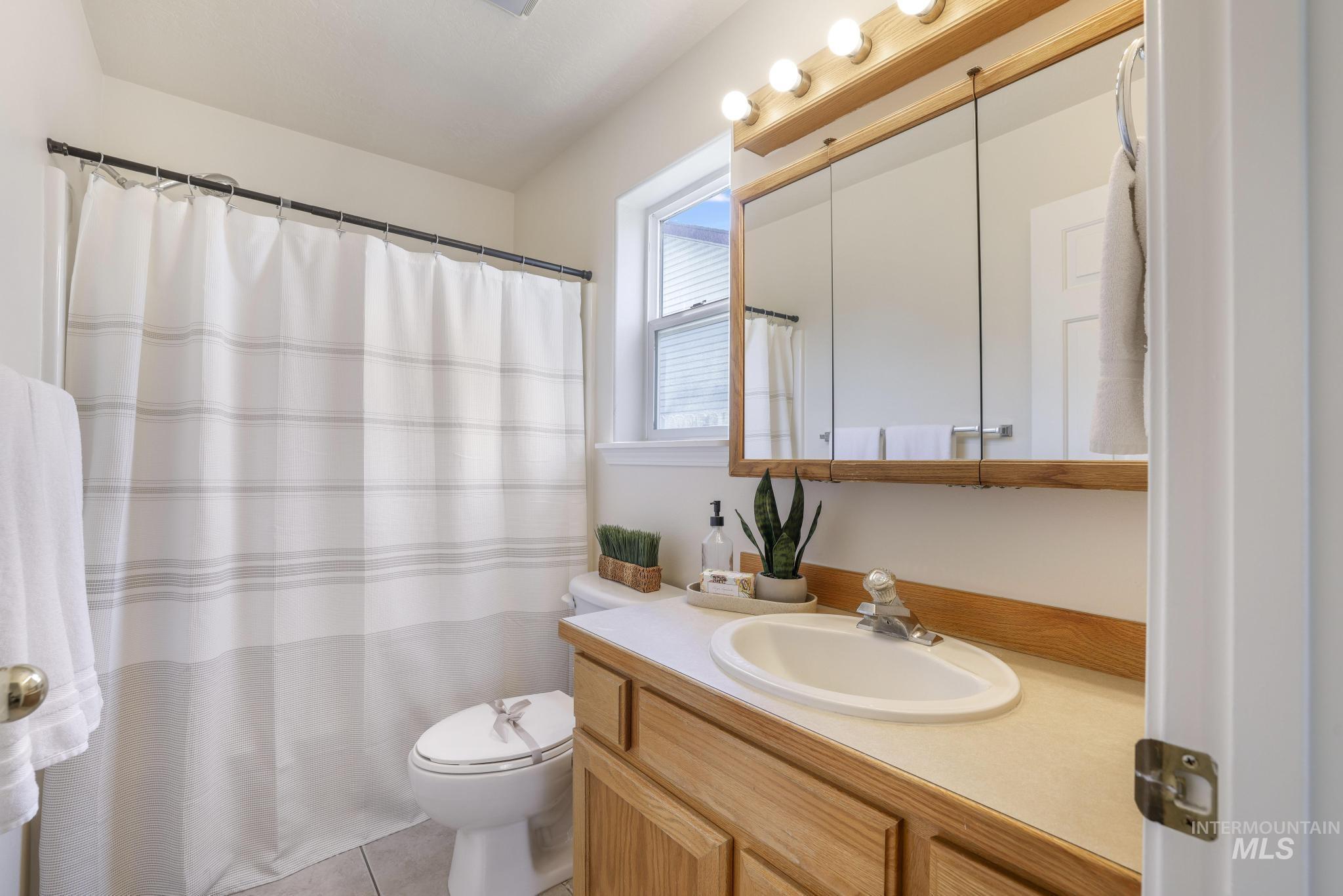 Bathroom featuring vanity, light tile patterned flooring, and curtained shower