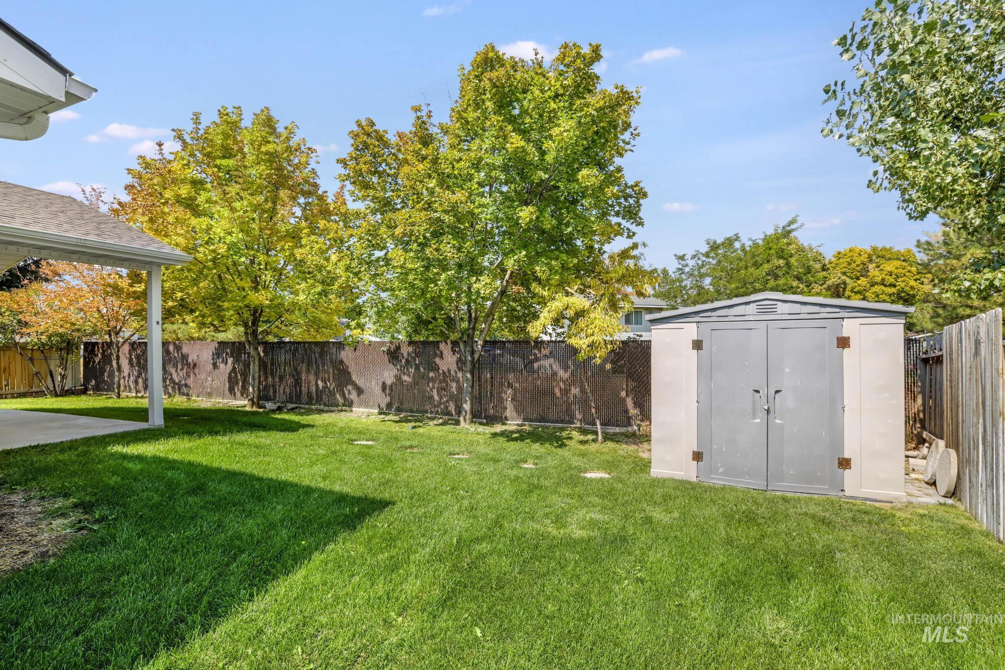 Fenced backyard with a shed and a patio area
