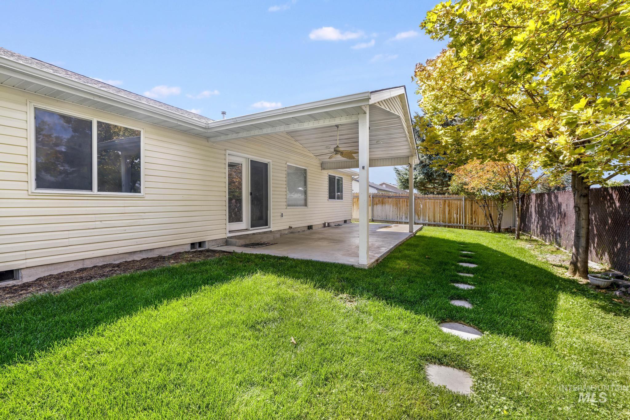 Fenced backyard with a patio area and a ceiling fan