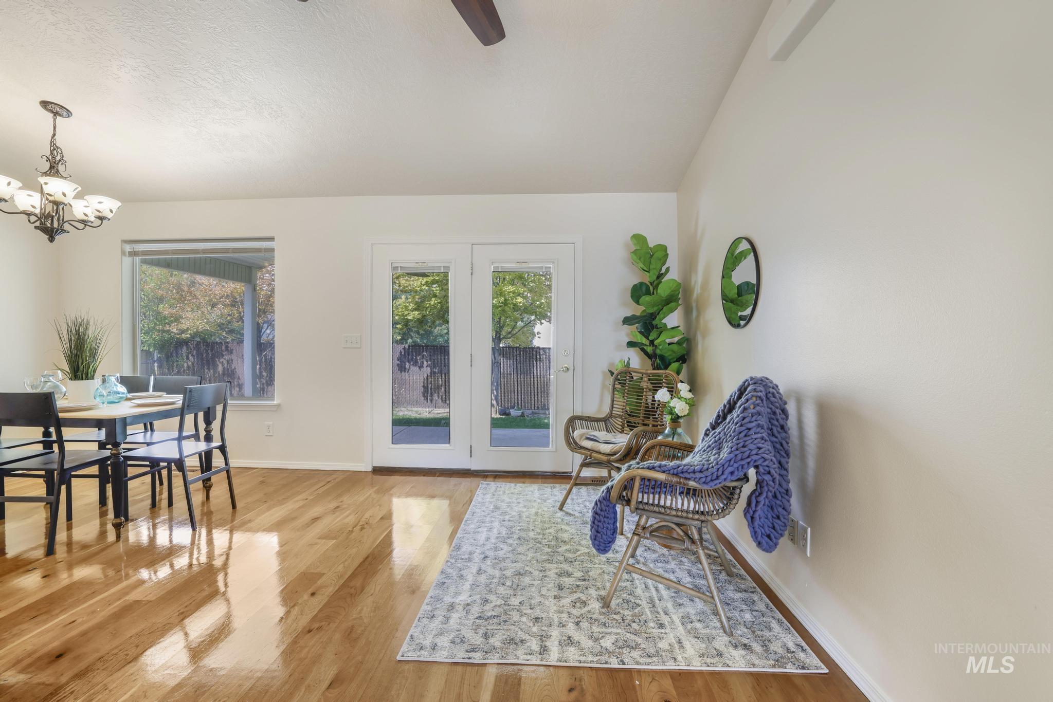 Sitting room featuring healthy amount of natural light, light wood-style flooring, a chandelier, and vaulted ceiling