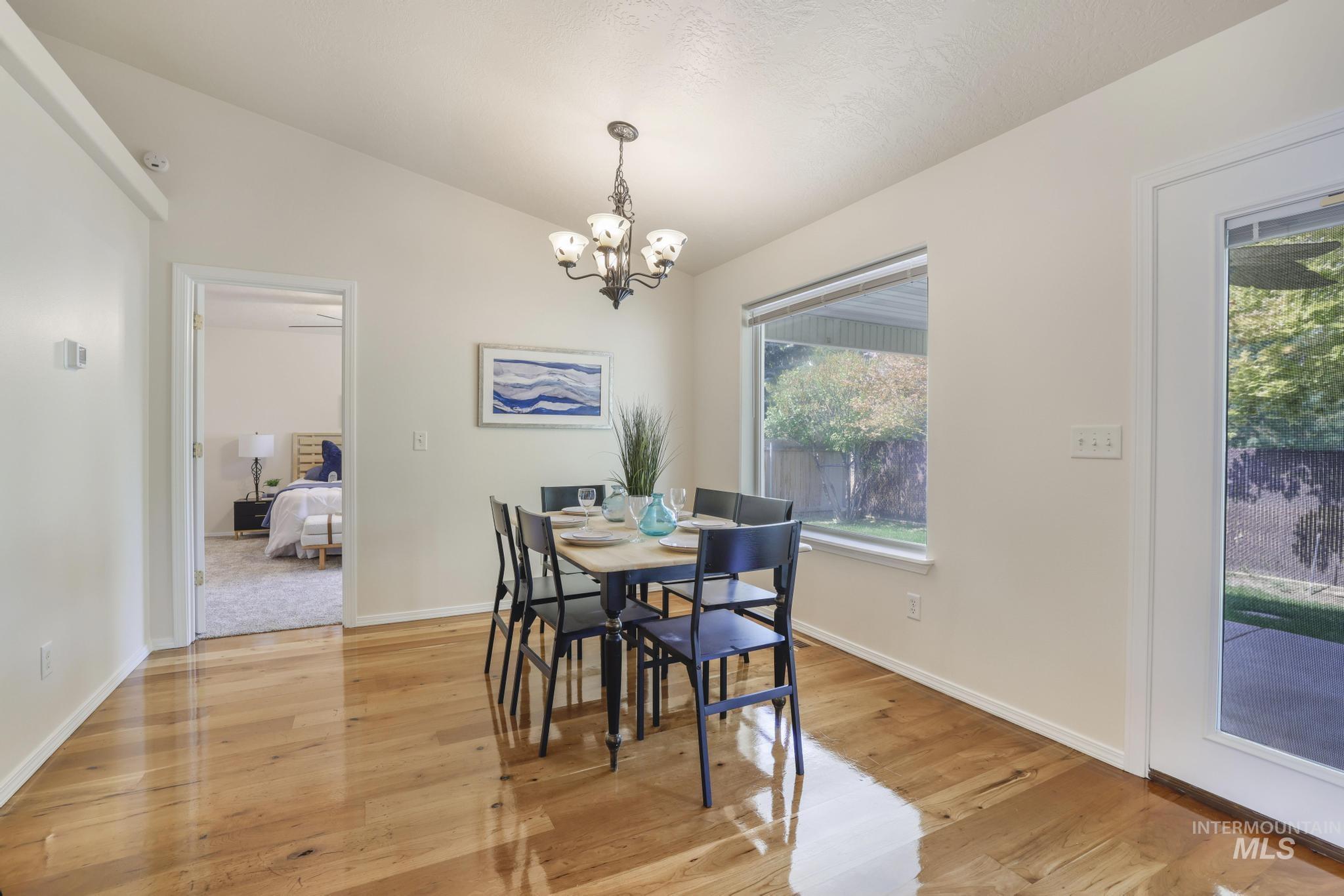 Dining room with vaulted ceiling, light wood-style floors, and a chandelier